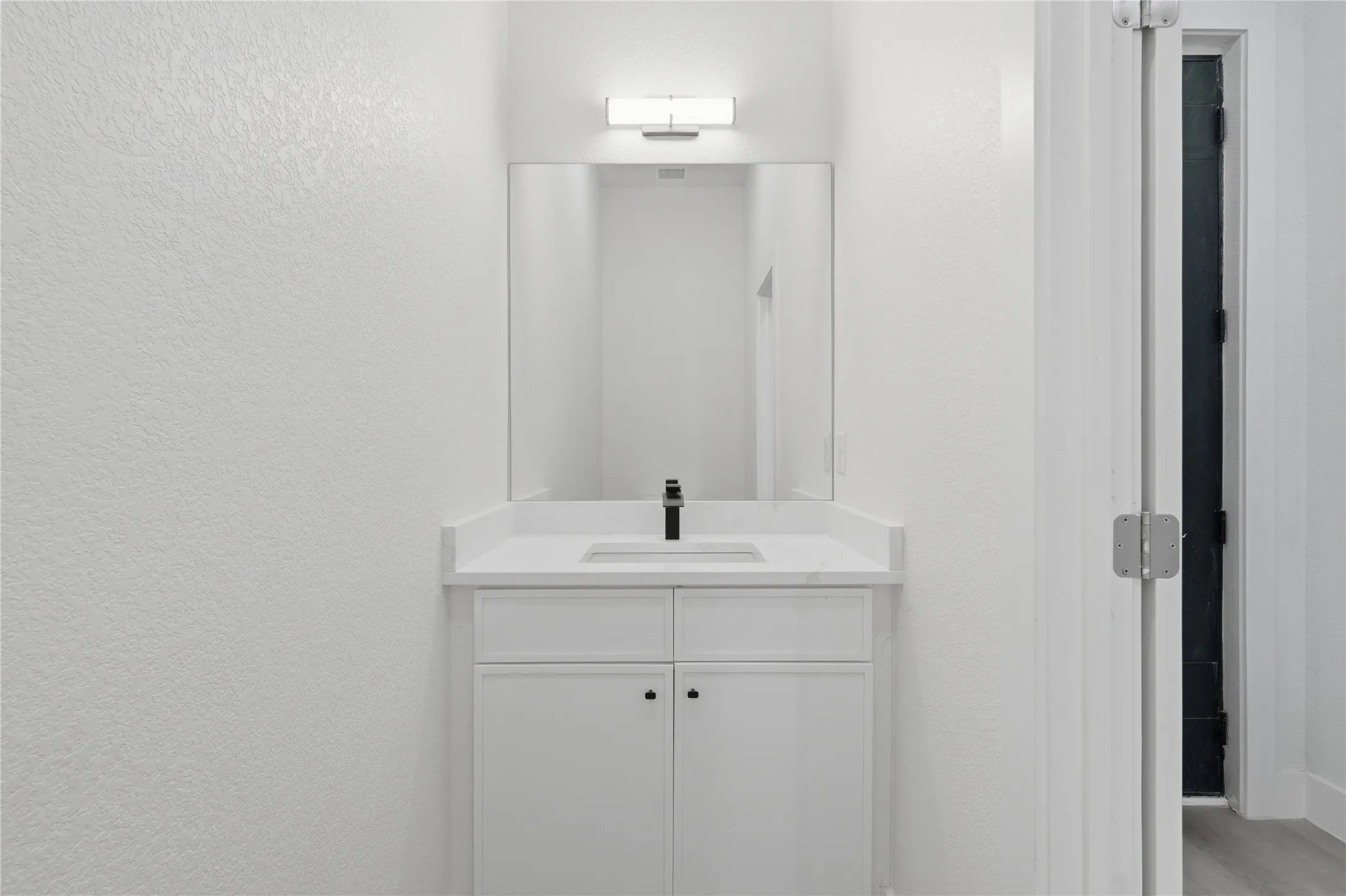 White shaker-style vanity with a white countertop and integrated sink