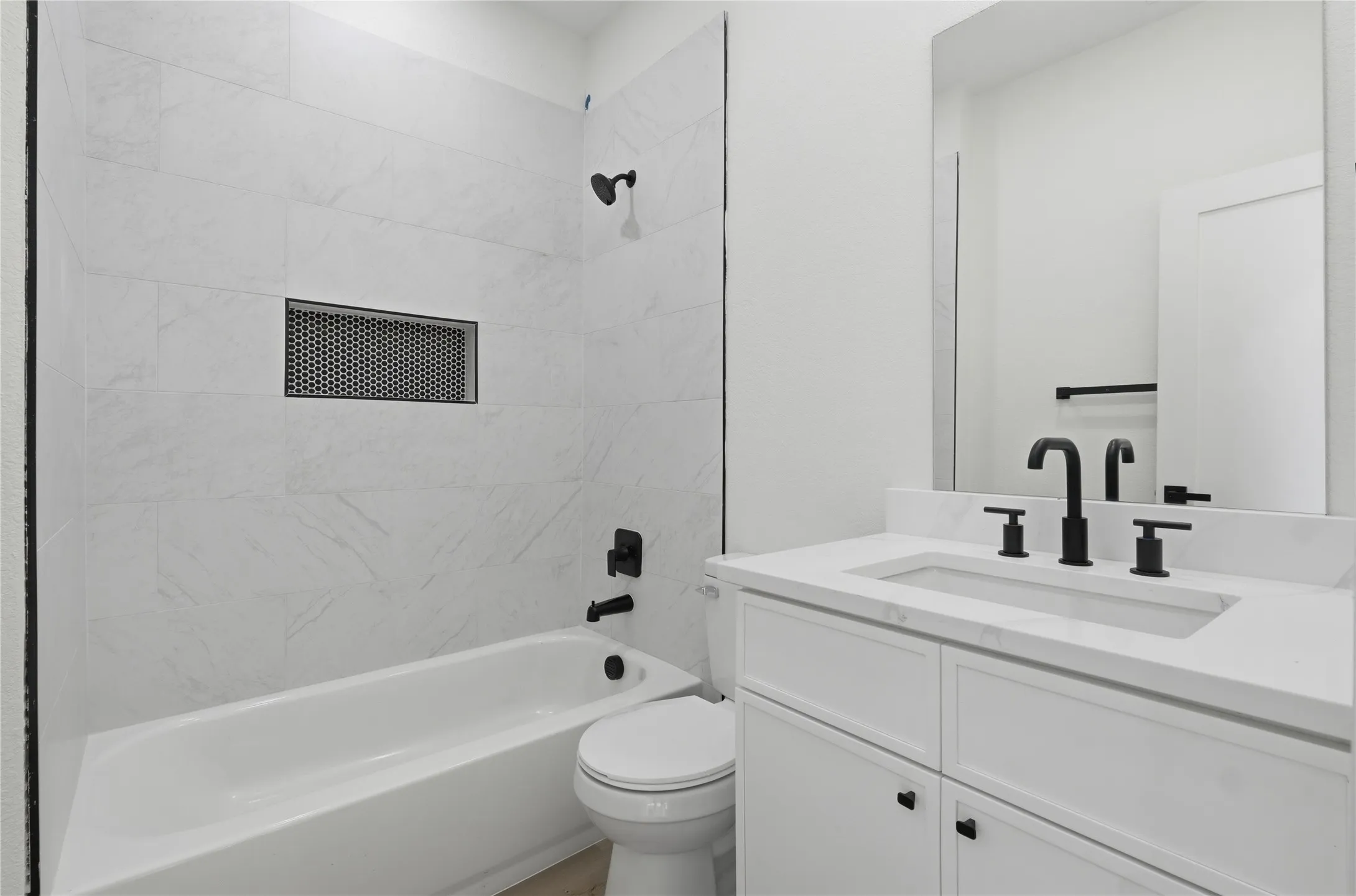 White vanity with an integrated rectangular sink, matte black two-handle faucet, and white cabinet storage