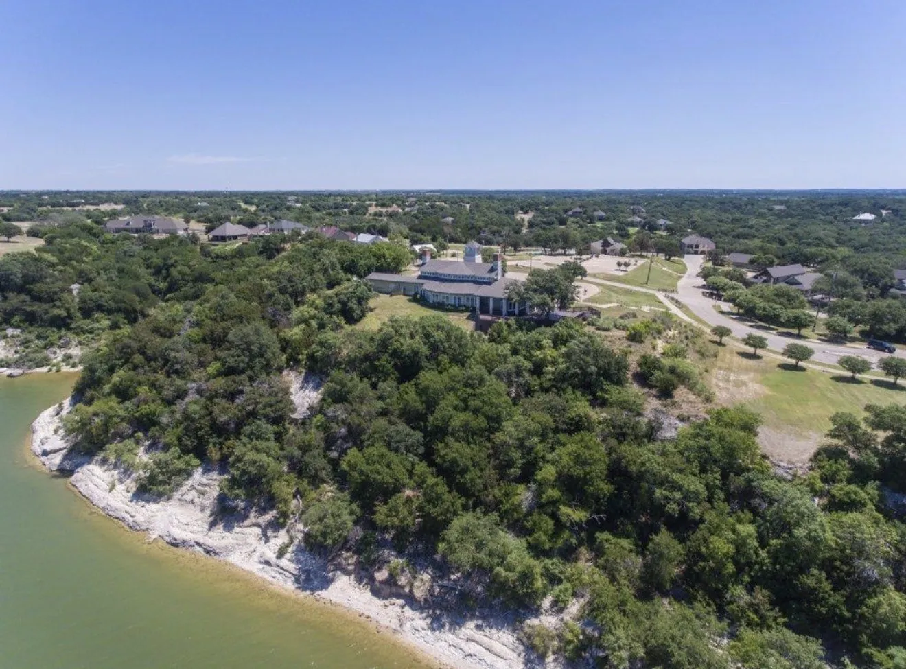Expansive waterfront property featuring a prominent building with a multi-gabled roof and surrounding paved areas