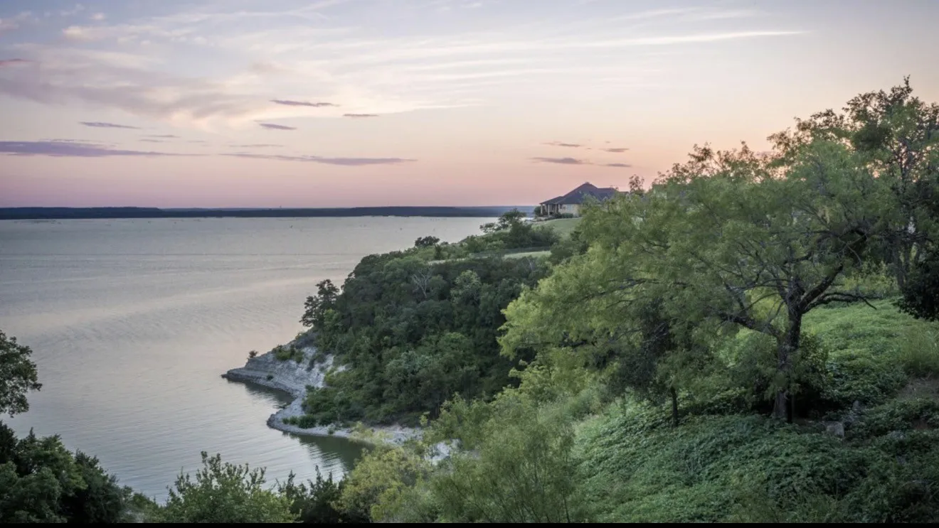 Expansive waterfront property featuring a terraced landscape and mature trees
