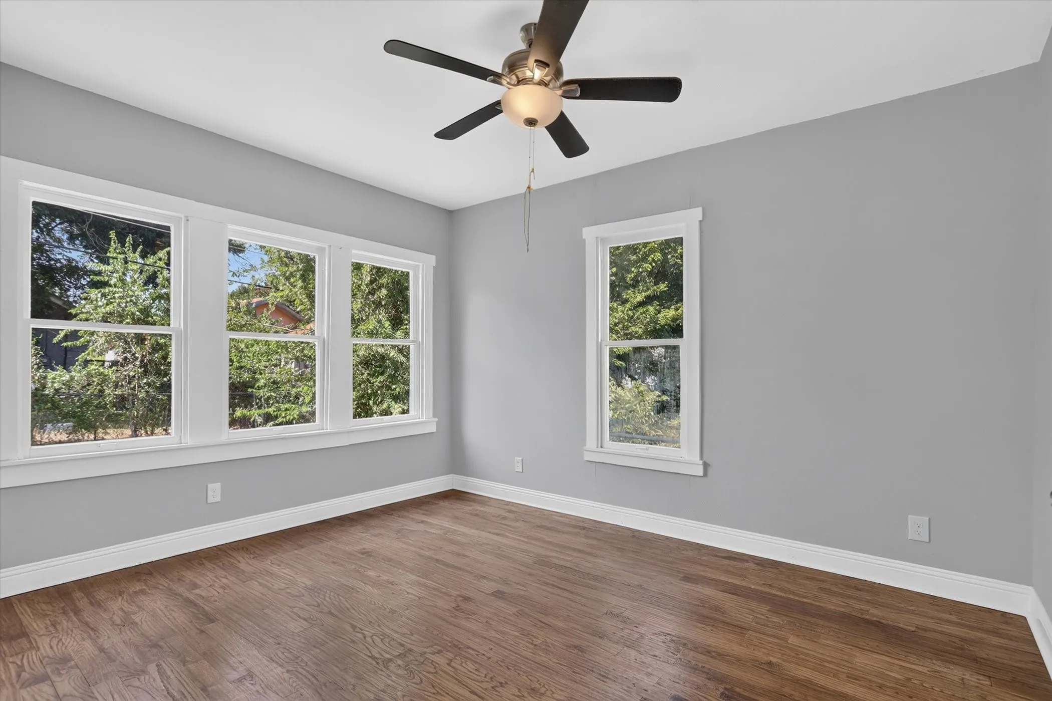 Spacious room with wood-finish flooring, light gray walls, and white trim