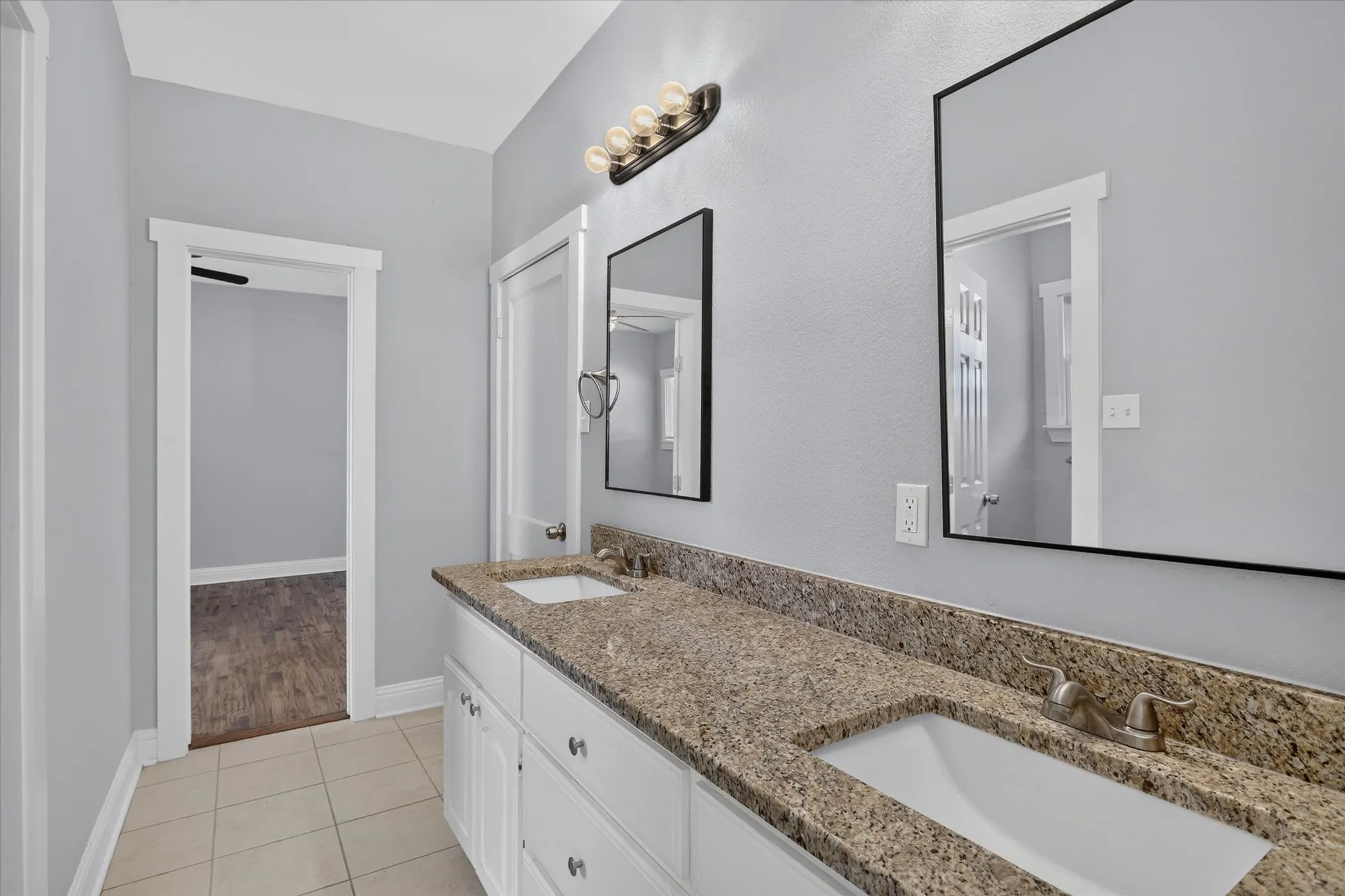 Double vanity with white cabinetry and granite-finish countertops featuring dual undermount sinks and brushed nickel faucets