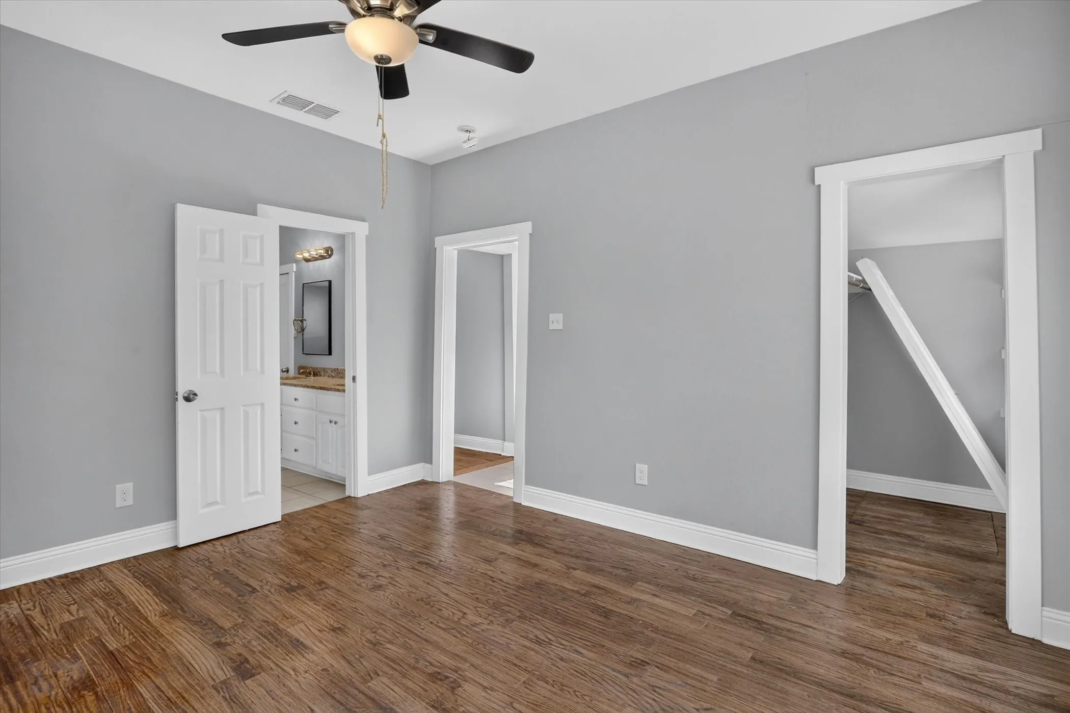 Spacious room featuring wood-finish flooring, light gray walls, and white trim