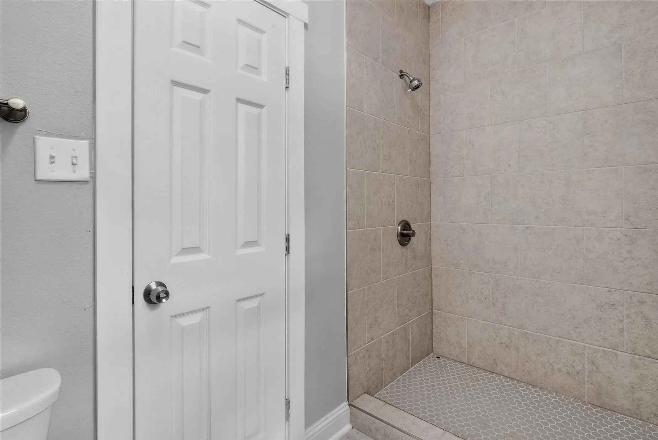 Tiled shower with a brushed nickel shower head and control