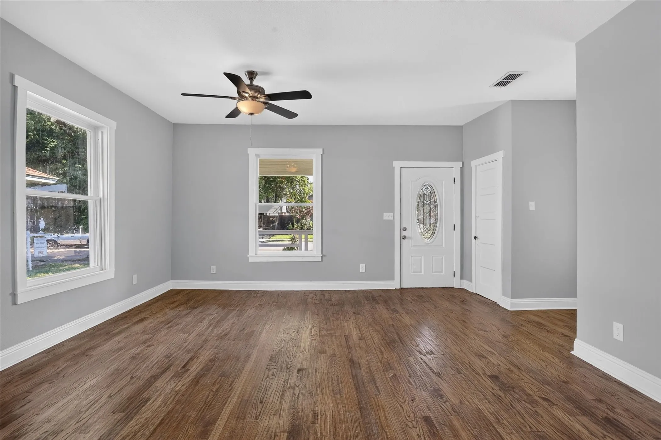 Spacious room featuring wood-finish flooring, light gray wall paint, and white trim