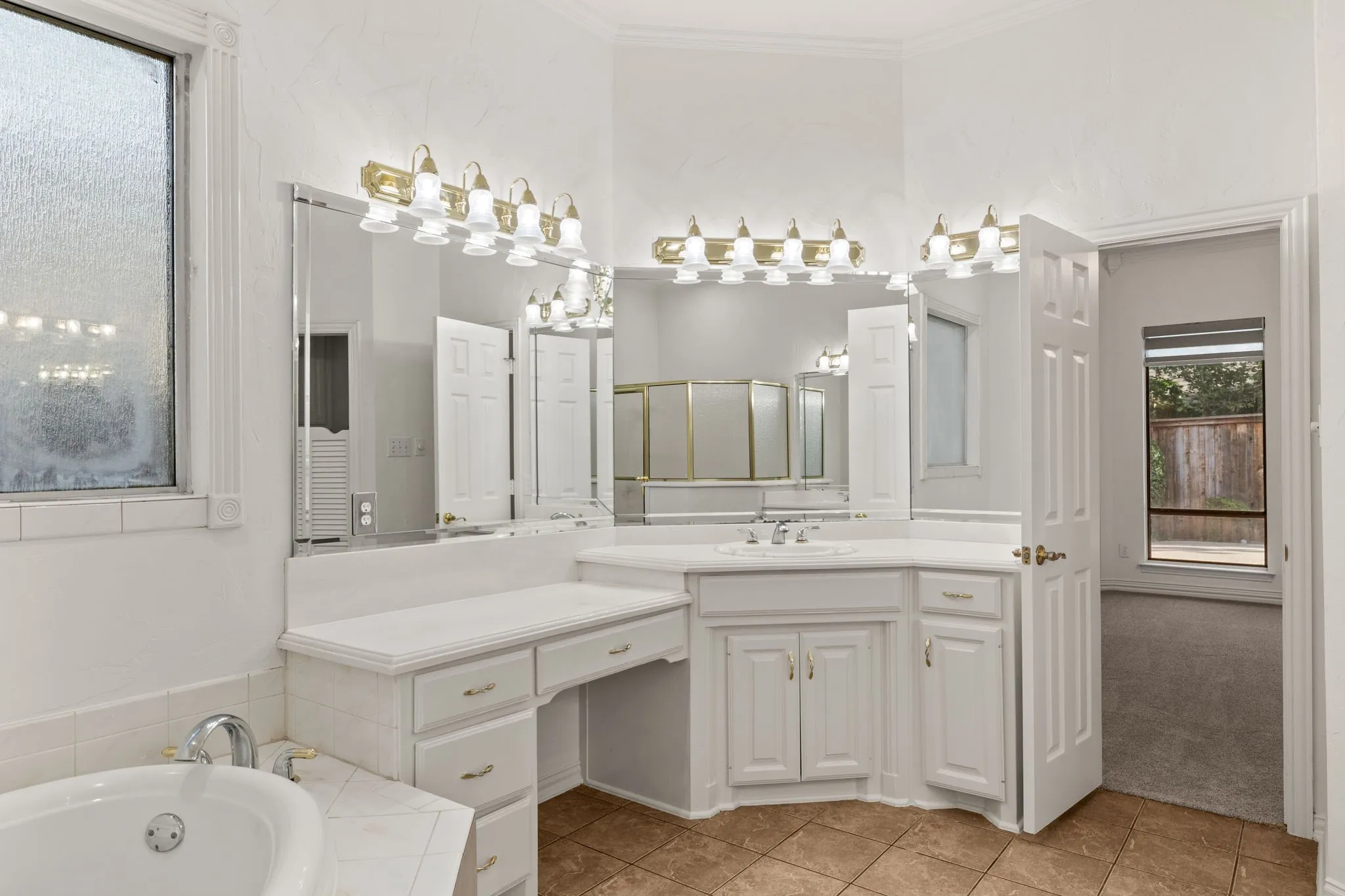 Bathroom with corner vanity featuring a built-in sink, gold-tone hardware, and bright wall-mounted lighting