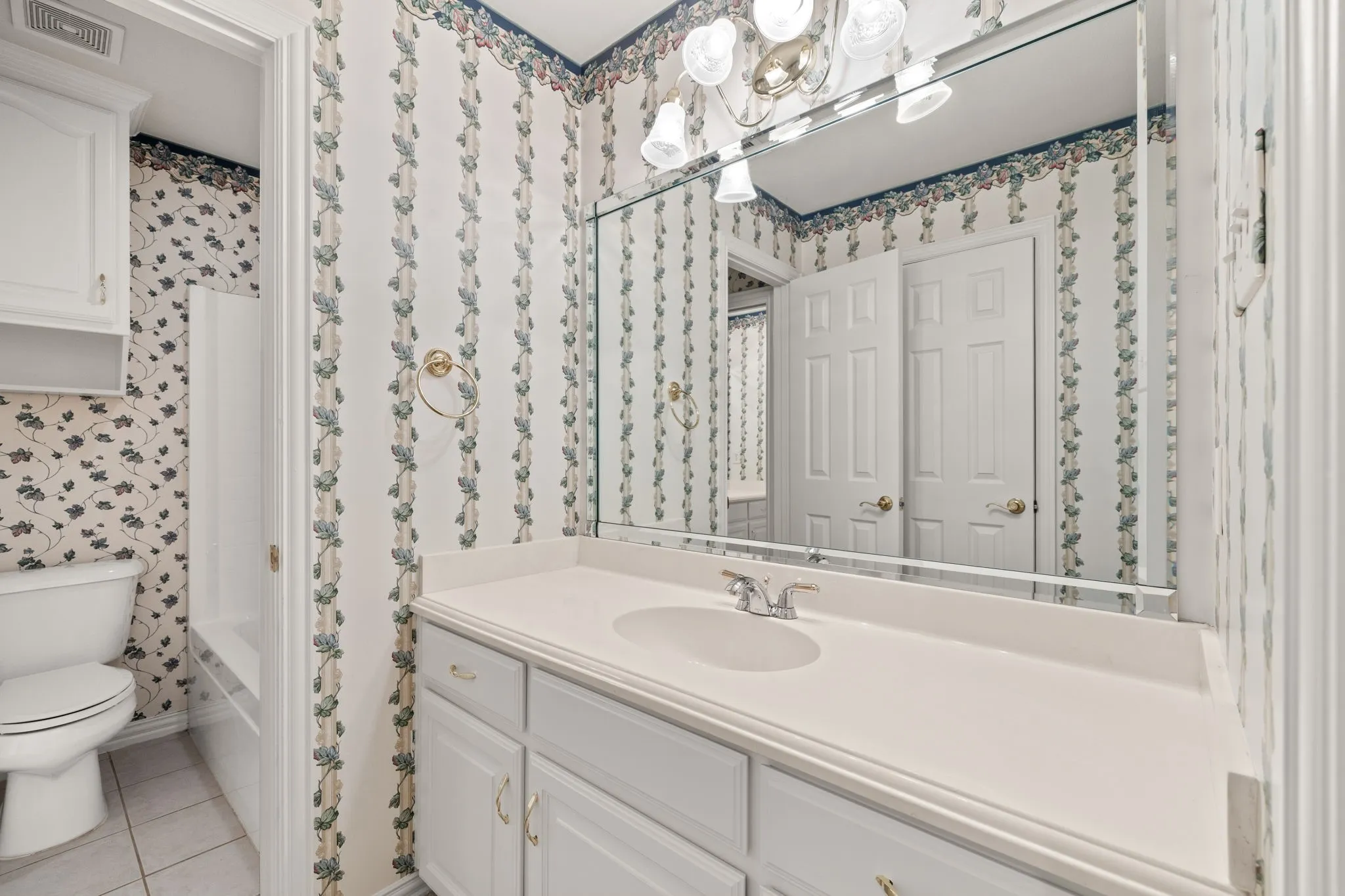 Bathroom vanity with a white countertop and integrated sink, chrome faucet, and under-sink cabinetry