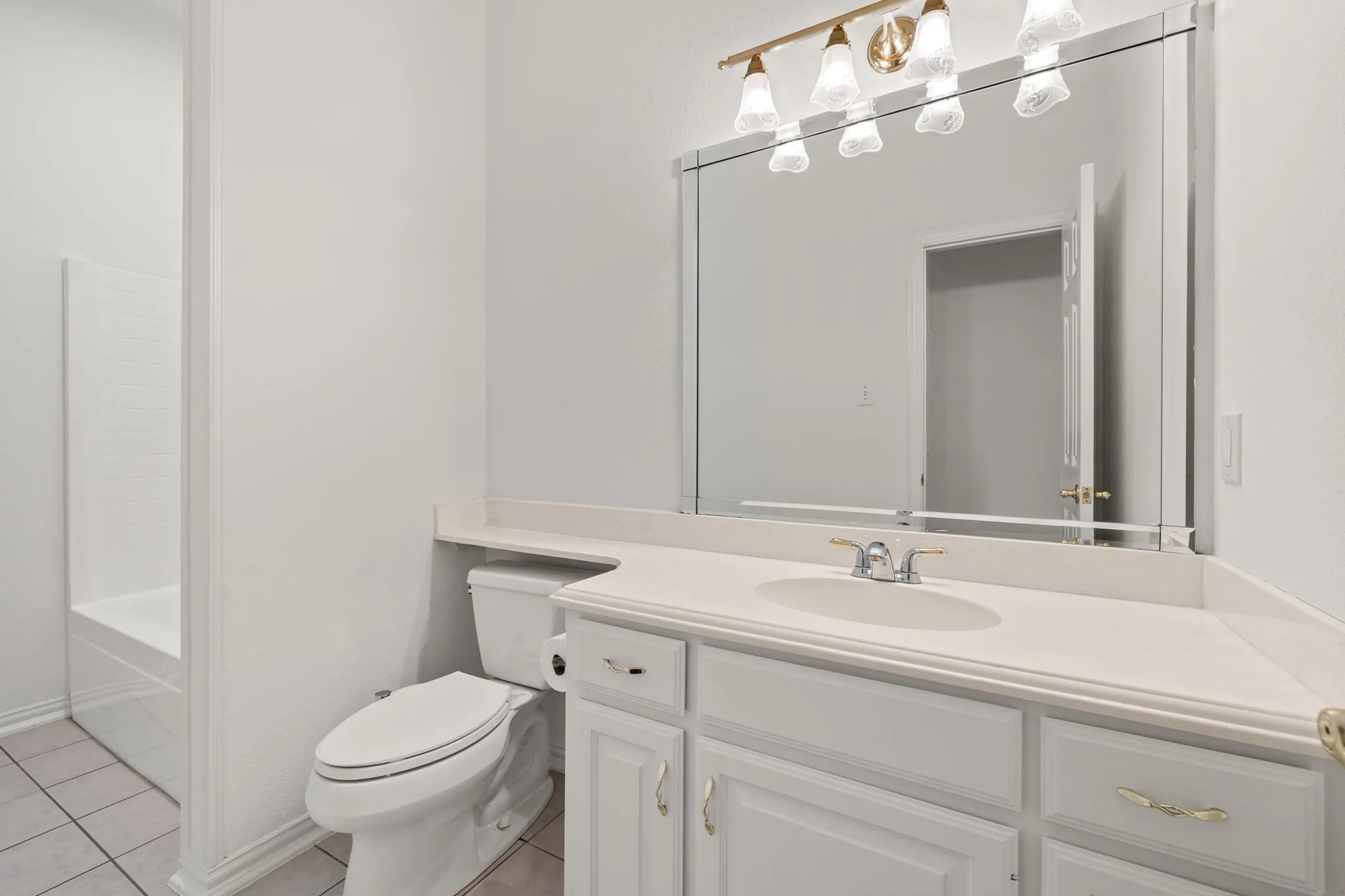 Bathroom featuring a white vanity with an integrated sink, polished chrome faucet, and a large wall-mounted mirror