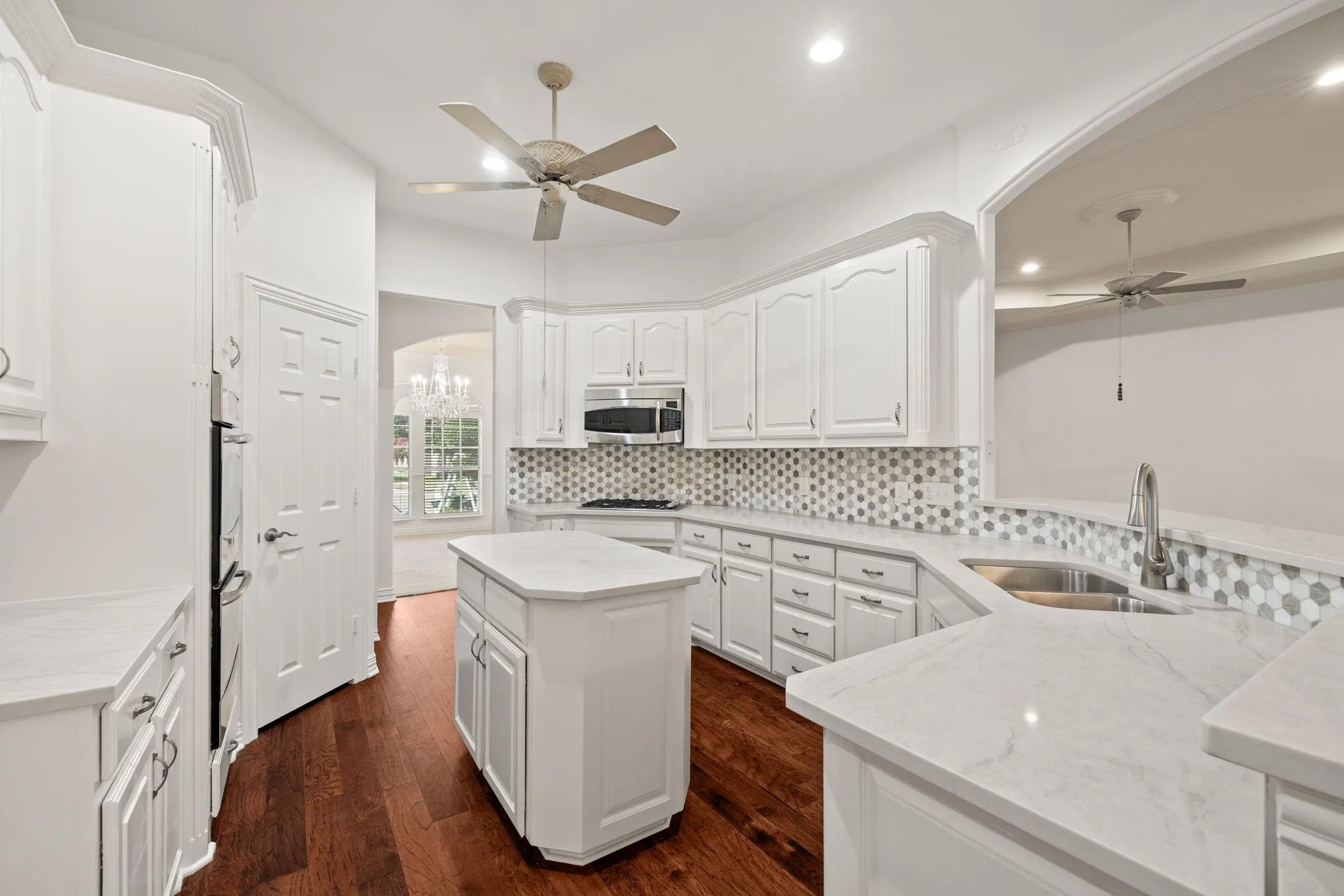 Kitchen featuring wood-finish flooring, white cabinetry, a central island, and light-toned countertops