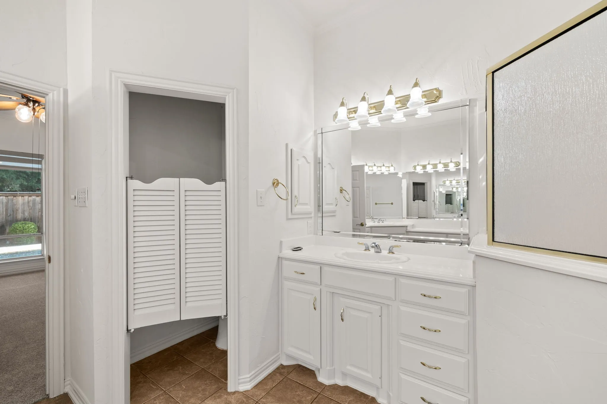 White bathroom vanity with a single basin, ample countertop space, and built-in cabinetry