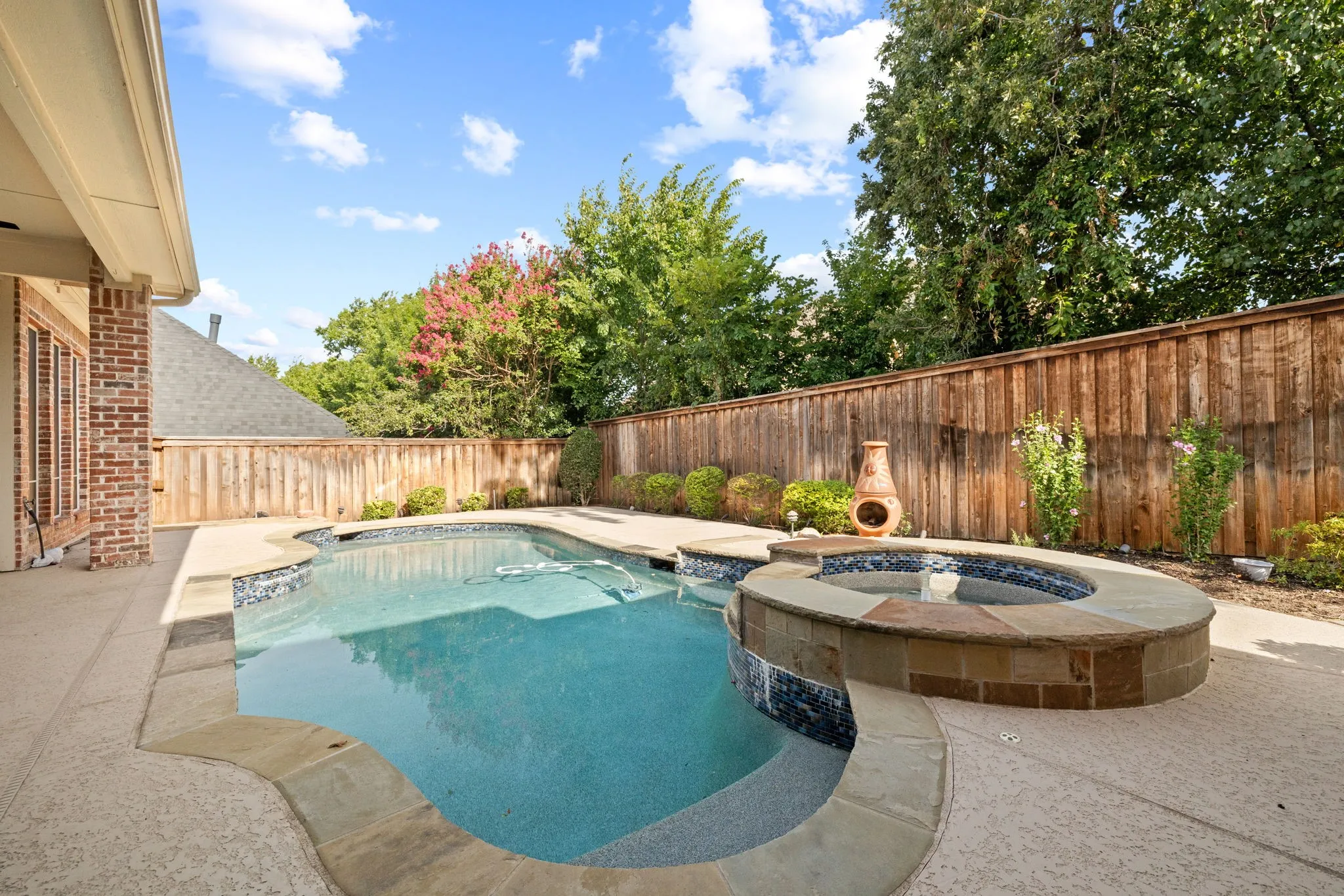Outdoor living space featuring a freeform swimming pool with integrated spa