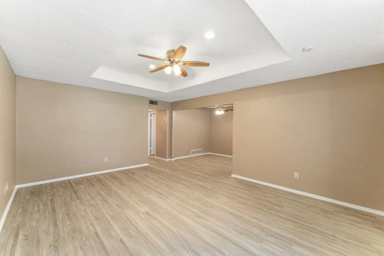 Spacious room featuring wood-finish flooring, neutral-toned walls, and white baseboards