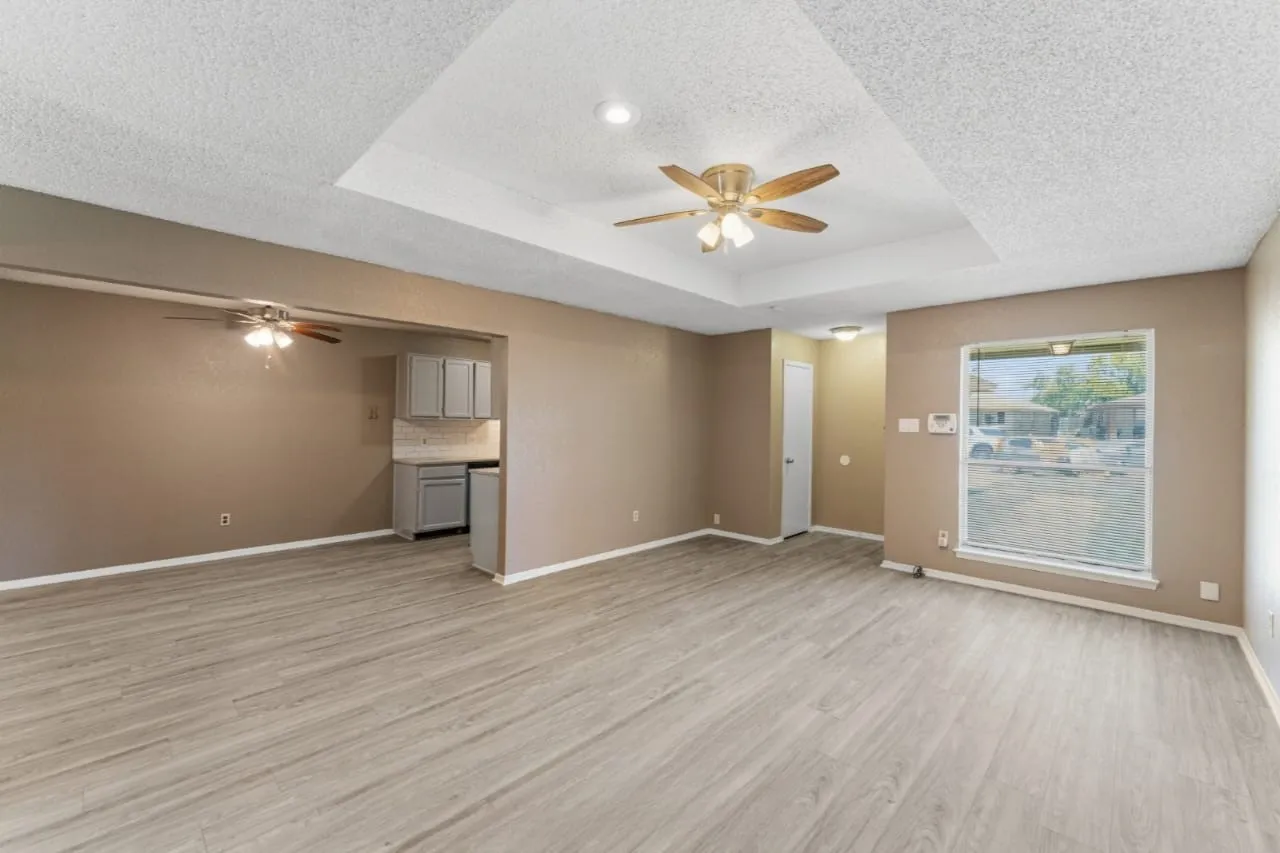 Spacious room featuring wood-finish flooring, a tray ceiling with a ceiling fan, and recessed lighting