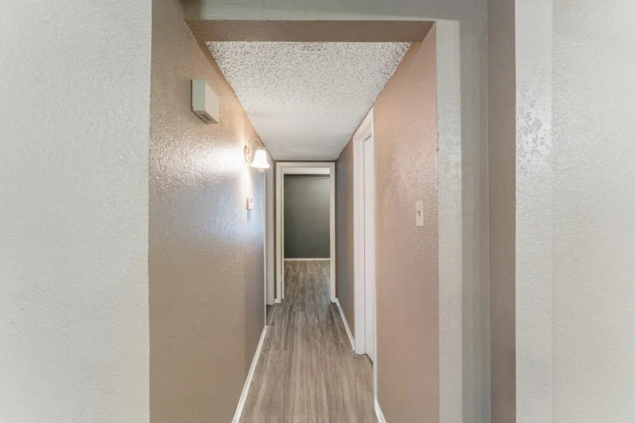 Hallway with neutral wall finishes and wood-finish flooring