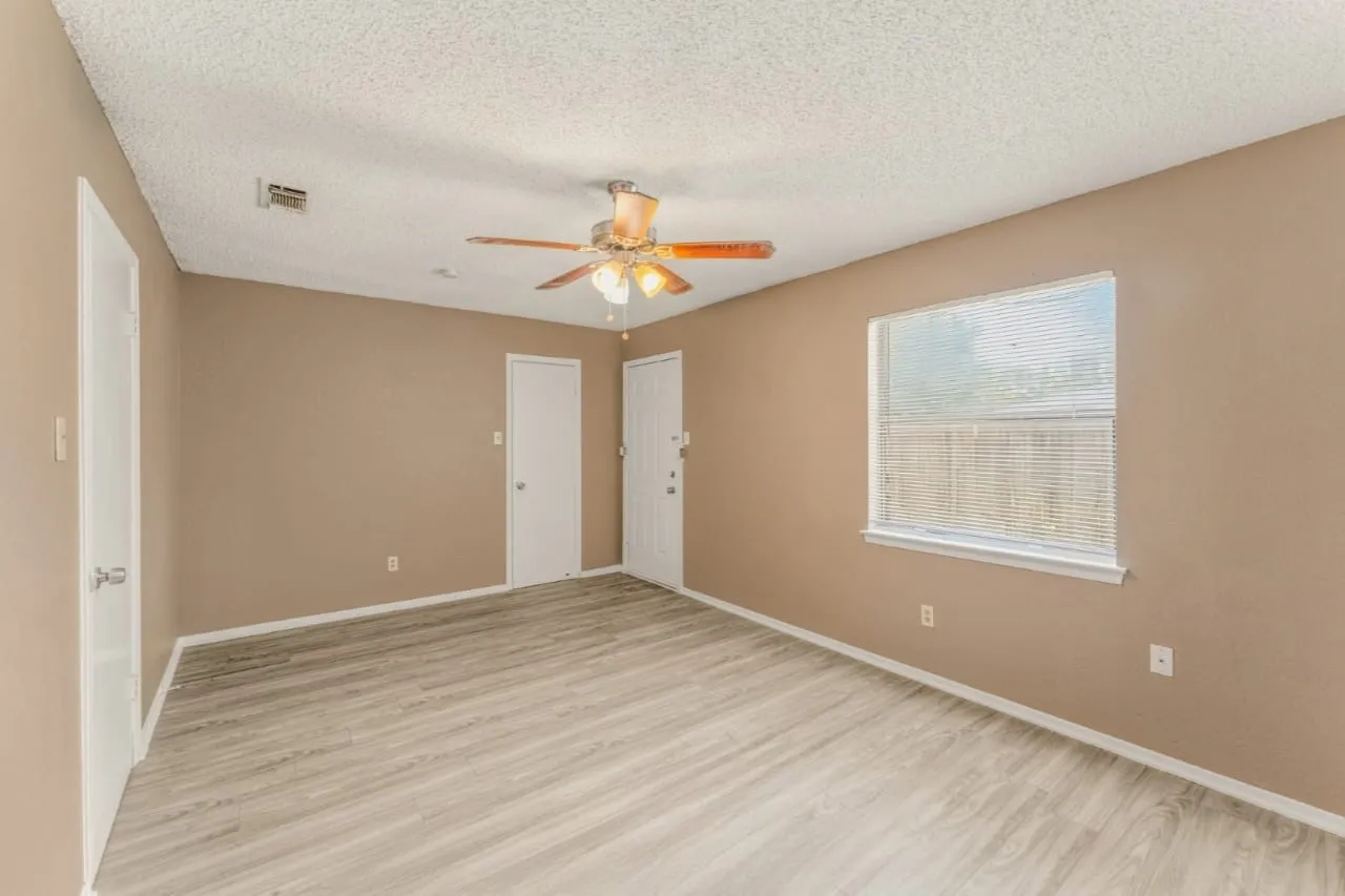 Spacious interior room featuring wood-finish flooring, neutral wall tones, and a textured ceiling