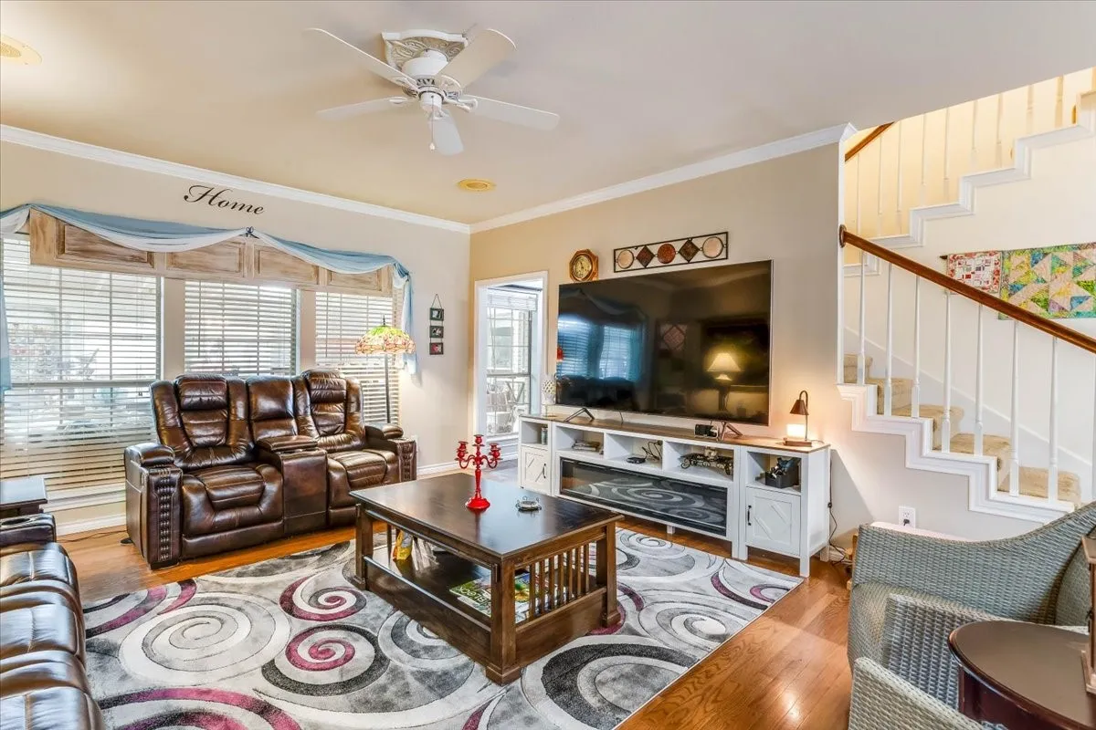 Spacious living area featuring wood-finish flooring and crown molding
