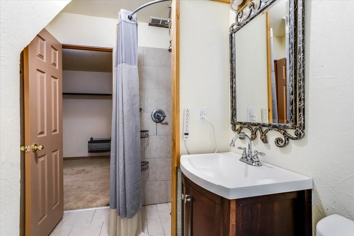 Bathroom featuring a dark wood-finish vanity with an integrated sink, a decorative framed mirror, and a tiled shower stall