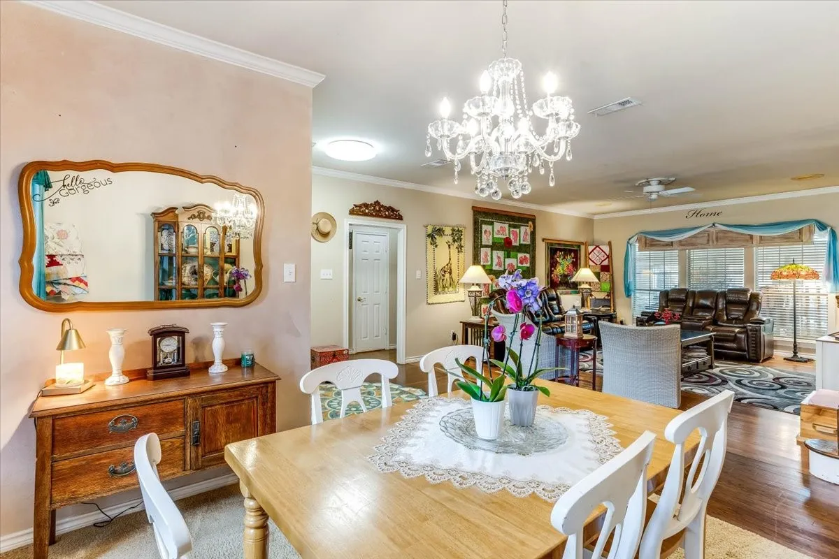 Dining area featuring a crystal chandelier, crown molding, and wood-finish flooring