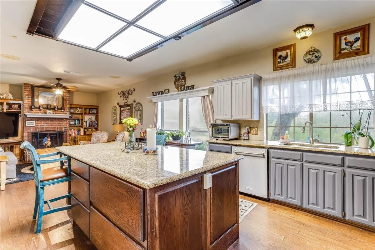 Kitchen featuring a central island with a light-toned countertop, wood-finish flooring, and a large skylight