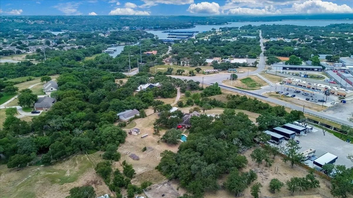 Expansive property featuring mature trees, a visible swimming pool, and multiple structures