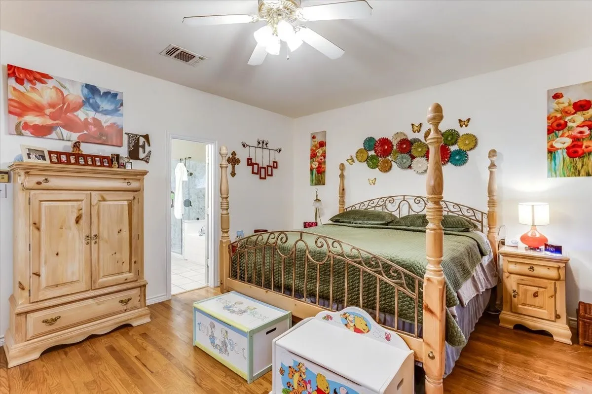Hardwood flooring throughout featuring white walls and a ceiling fan