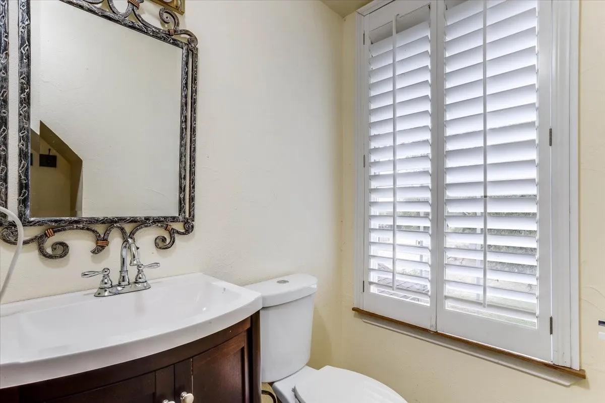 Bathroom vanity with a white ceramic sink, chrome faucet, and decorative framed mirror