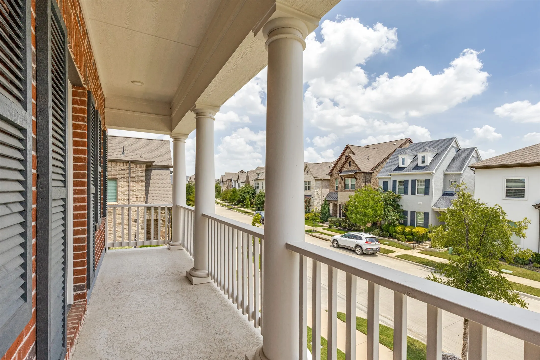 Second-story balcony featuring brick exterior, decorative shutters, and white architectural​​‌​​​​‌​​‌‌​‌‌​​​‌‌​‌​‌​‌​​​‌​​ columns