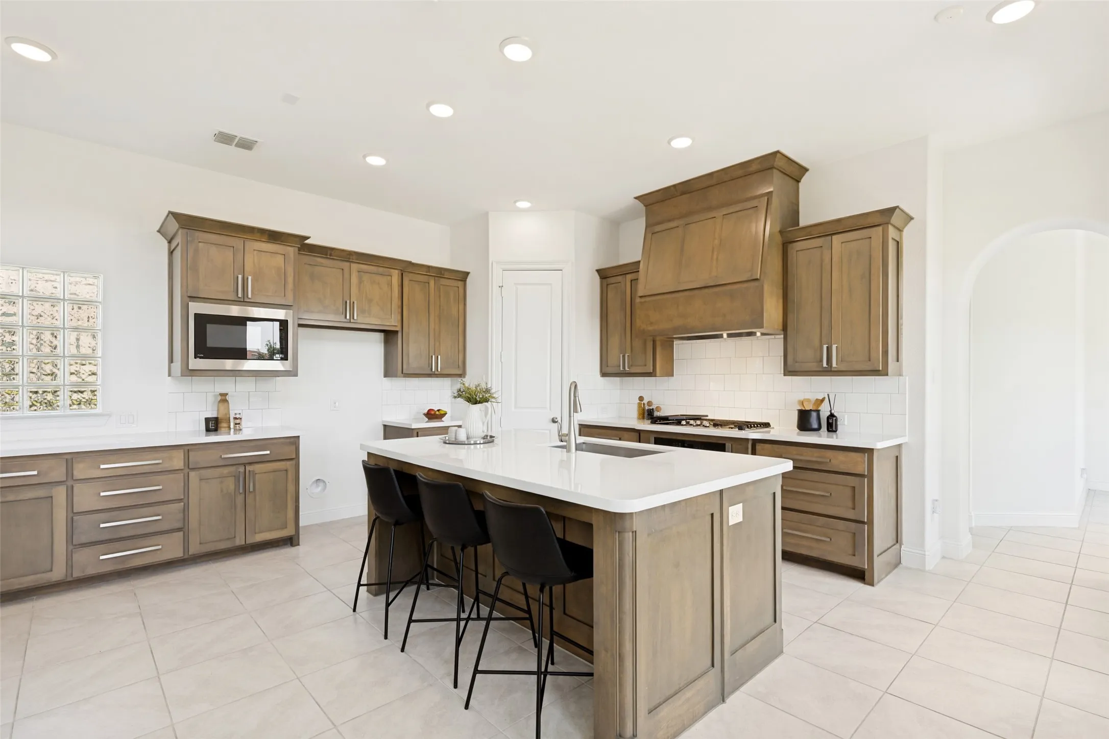 Kitchen featuring a large central island, white countertops, built-in microwave, wood-finish cabinetry, and recessed lighting