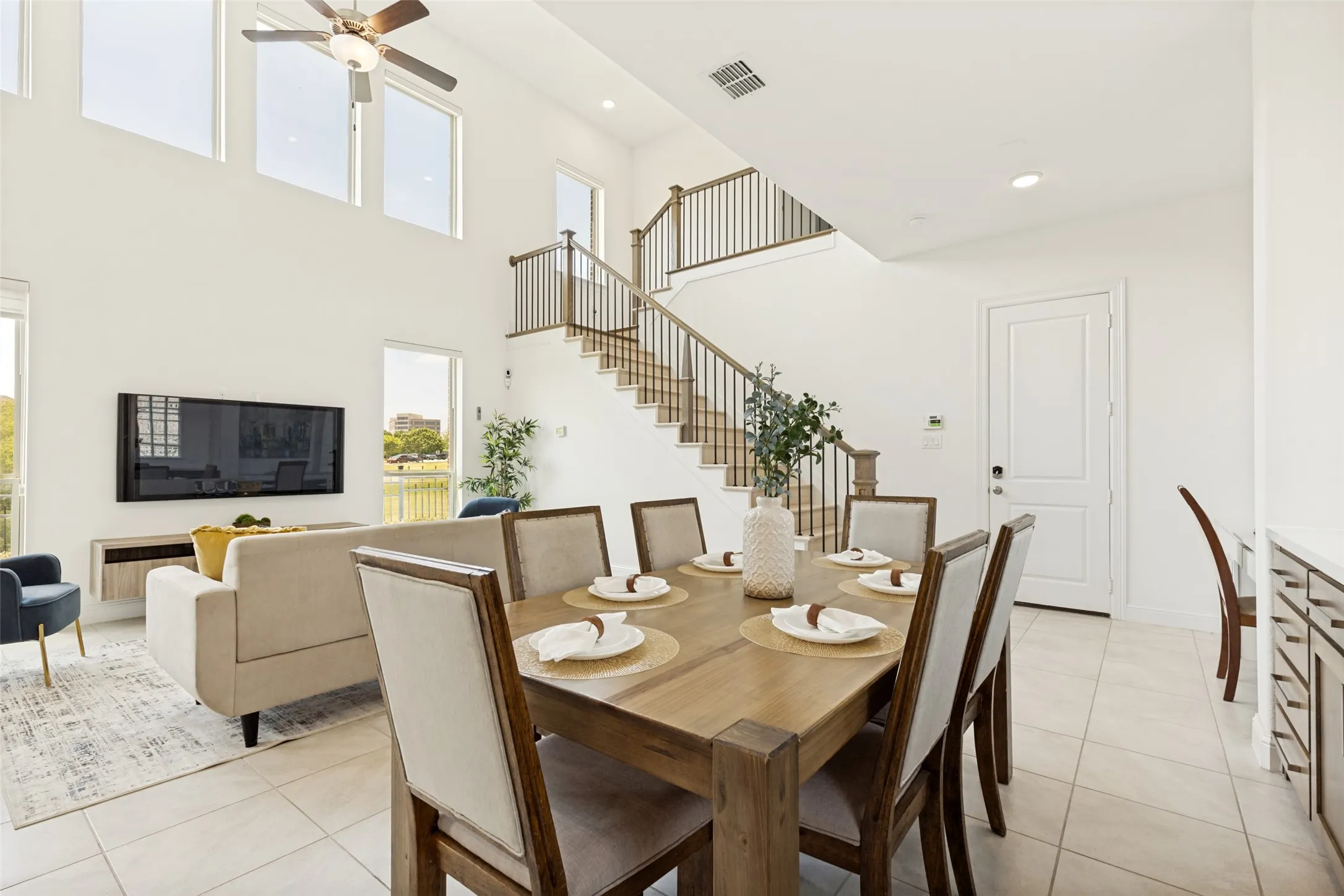 Dining area featuring a wood-finish table, tile flooring, and direct sightlines to the two-story living space