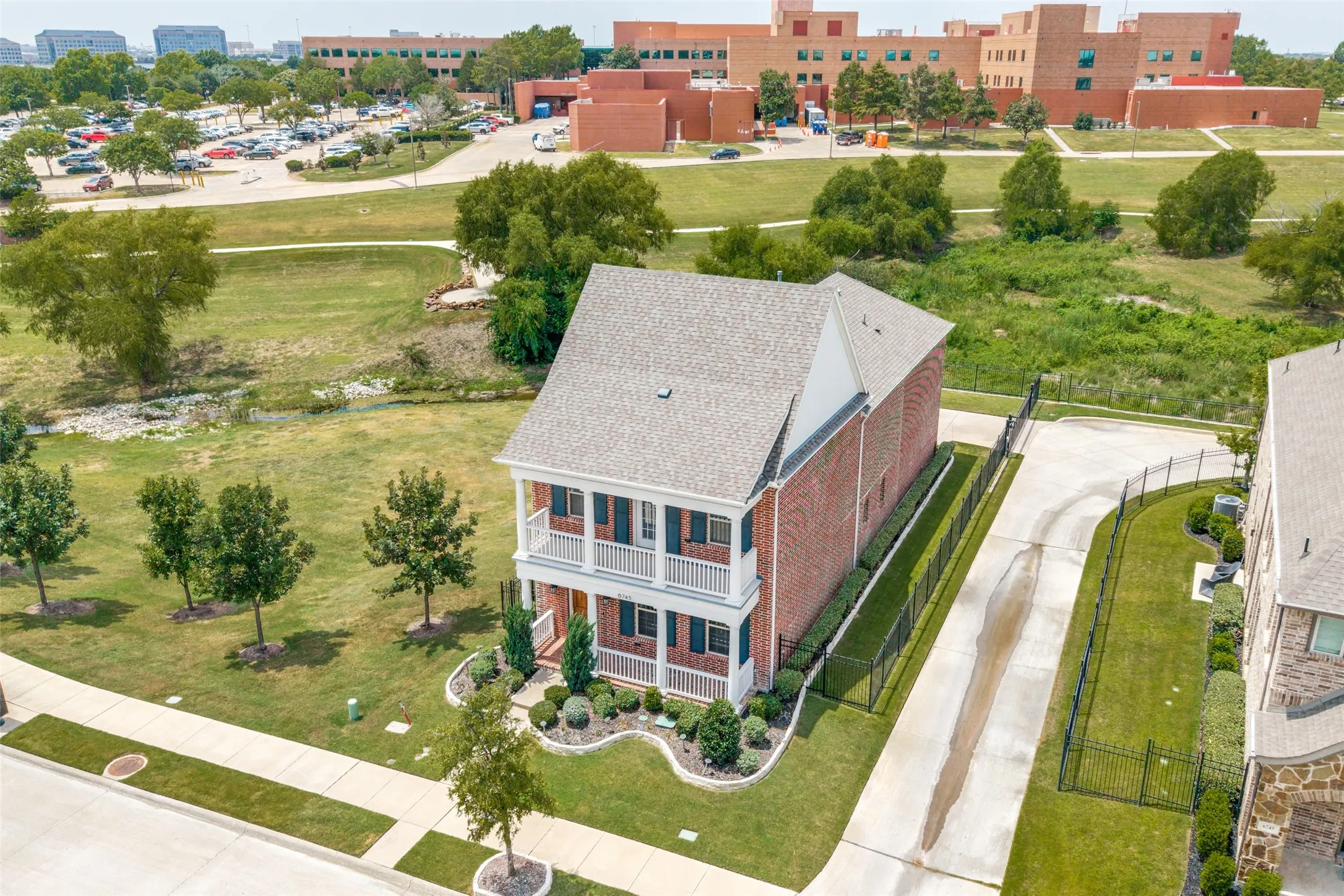 Two-story brick exterior with dual balconies, a gabled roof, and a paved private driveway