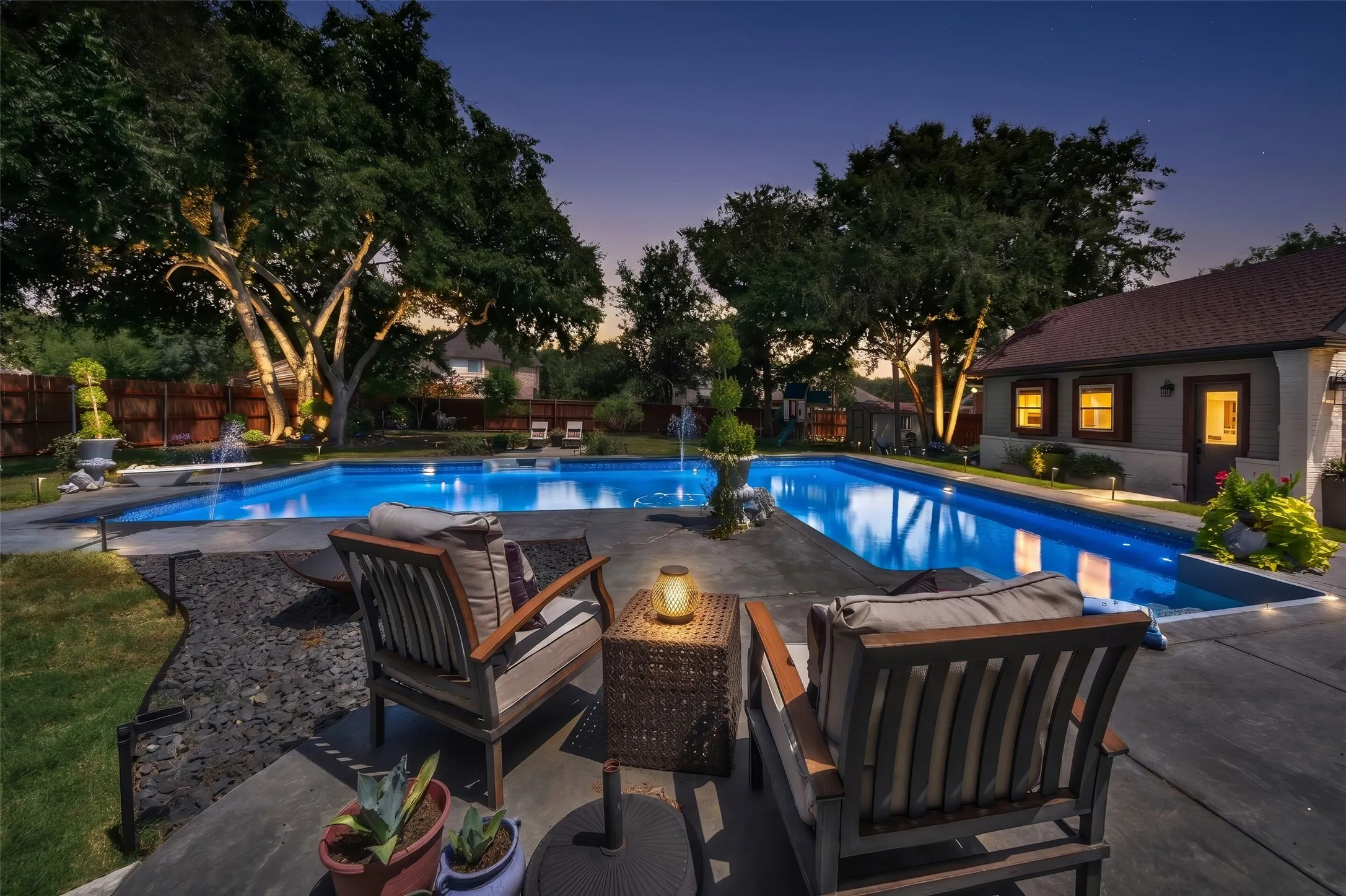 Professional lighting in front and back yards highlights mature trees.