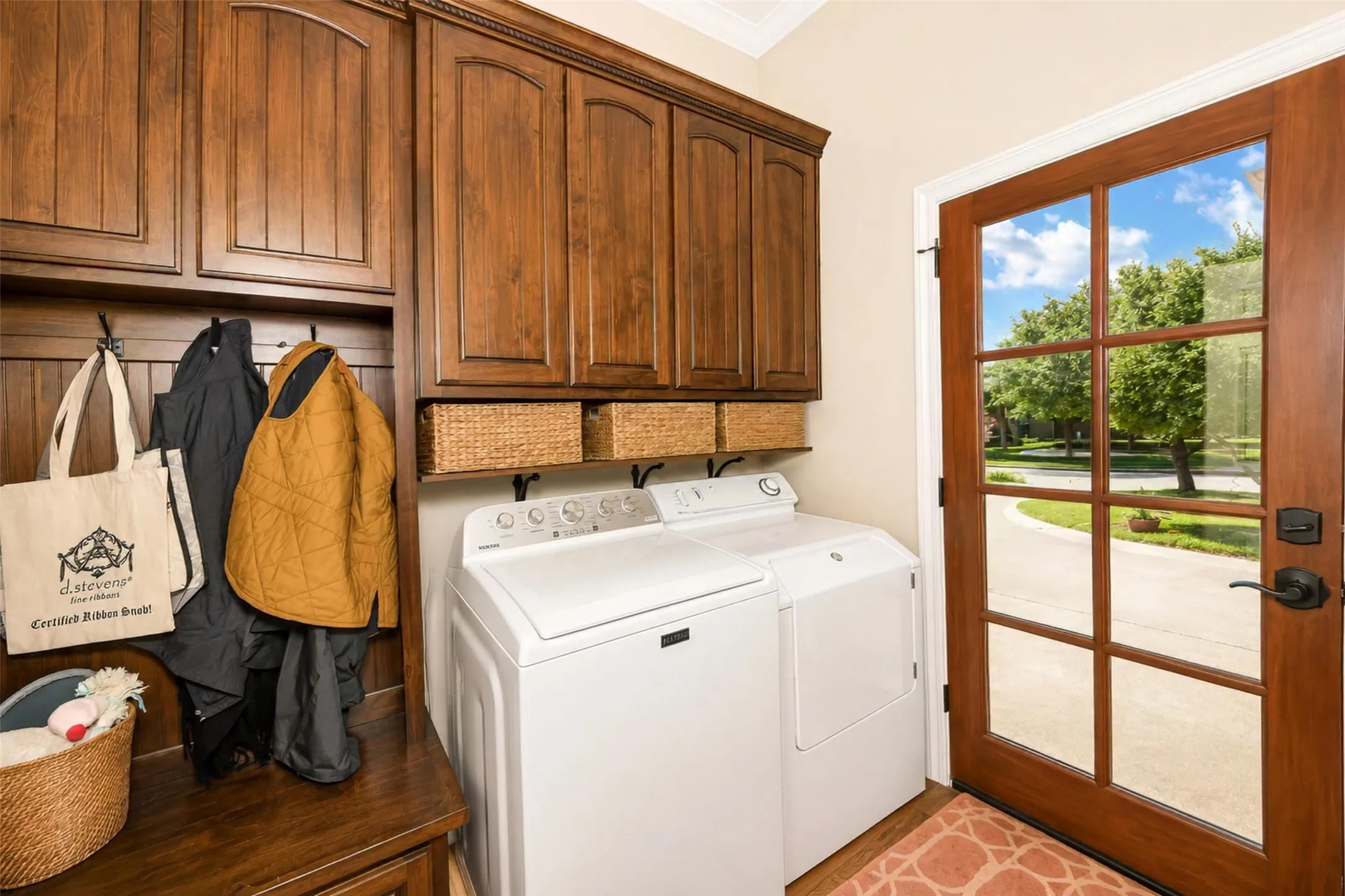 Laundry is located off the kitchen with custom cabinetry, wood flooring and a new mahogany wood door.