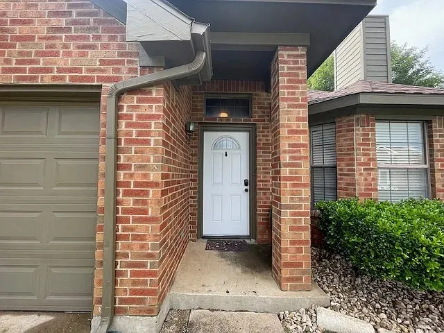 Brick exterior with a covered entry, featuring a white paneled front door with an arched lite