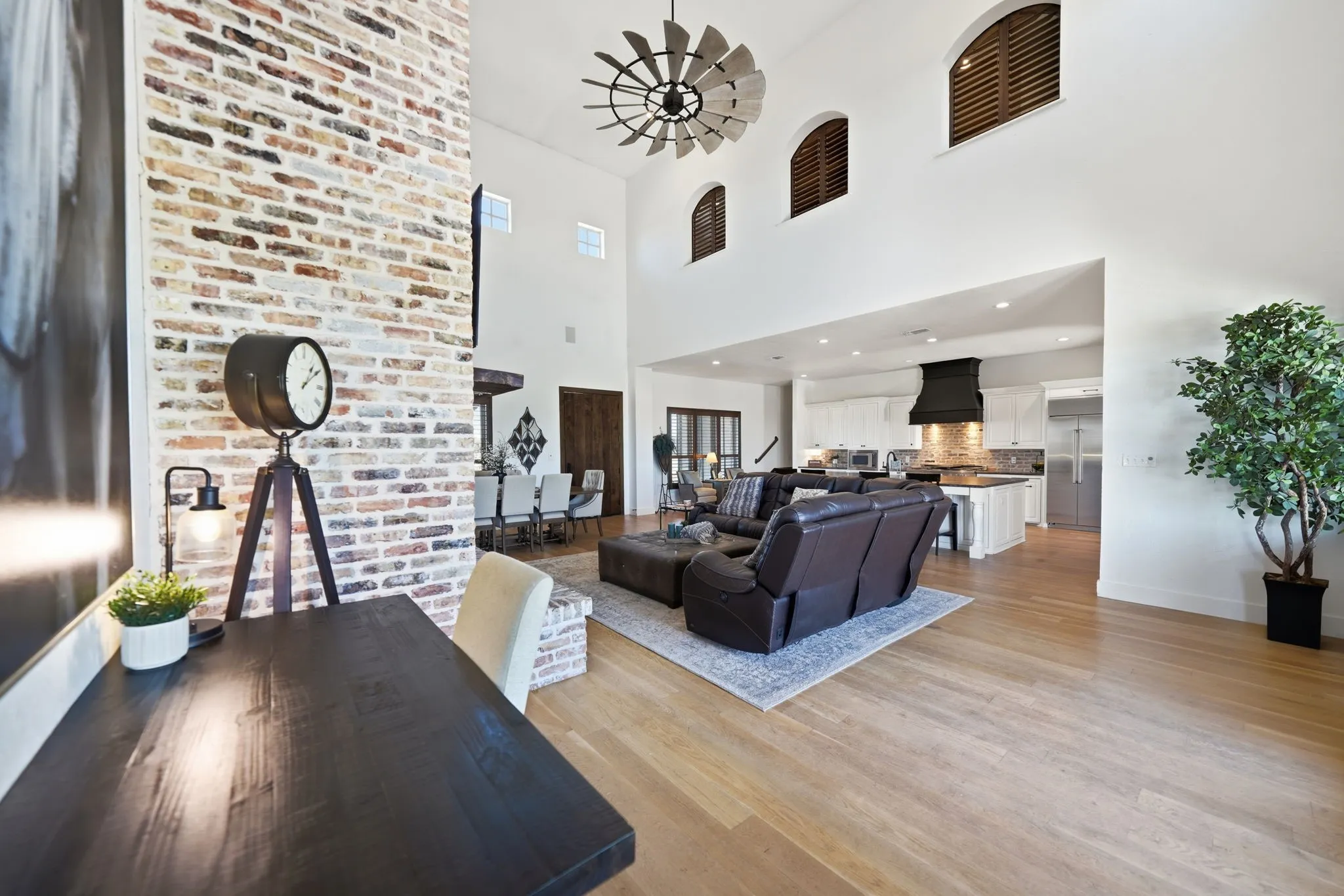 Spacious interior featuring a towering brick accent wall, high vaulted ceilings, and light wood-finish flooring