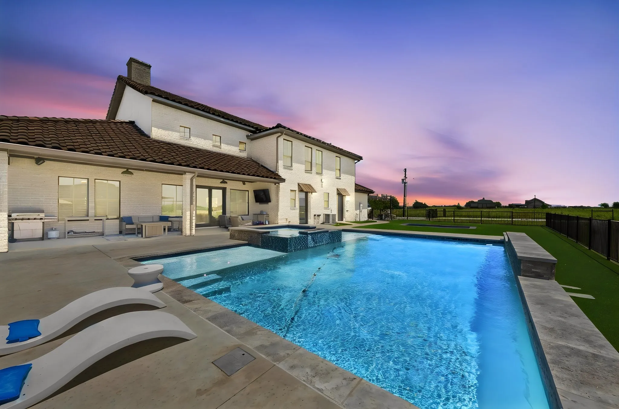 Expansive outdoor living area featuring a large swimming pool, integrated spa, and spacious concrete patio