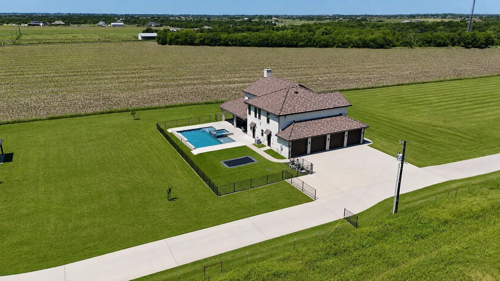 Expansive property featuring a two-story residence with a multi-car garage, a fenced swimming pool, and a large concrete driveway