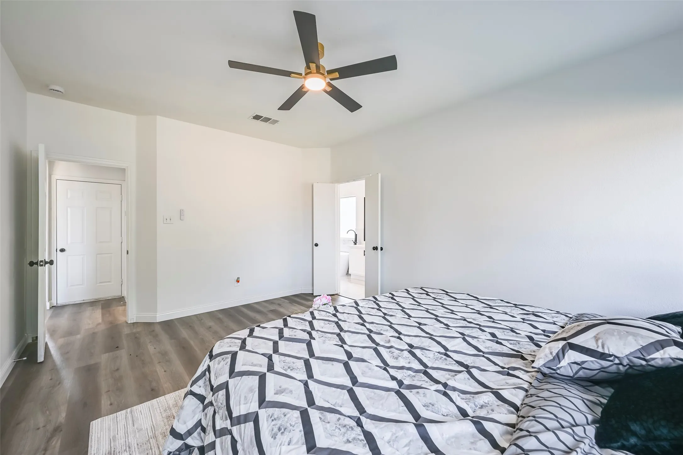Spacious room featuring wood-finish flooring, white walls, and a ceiling fan with integrated lighting
