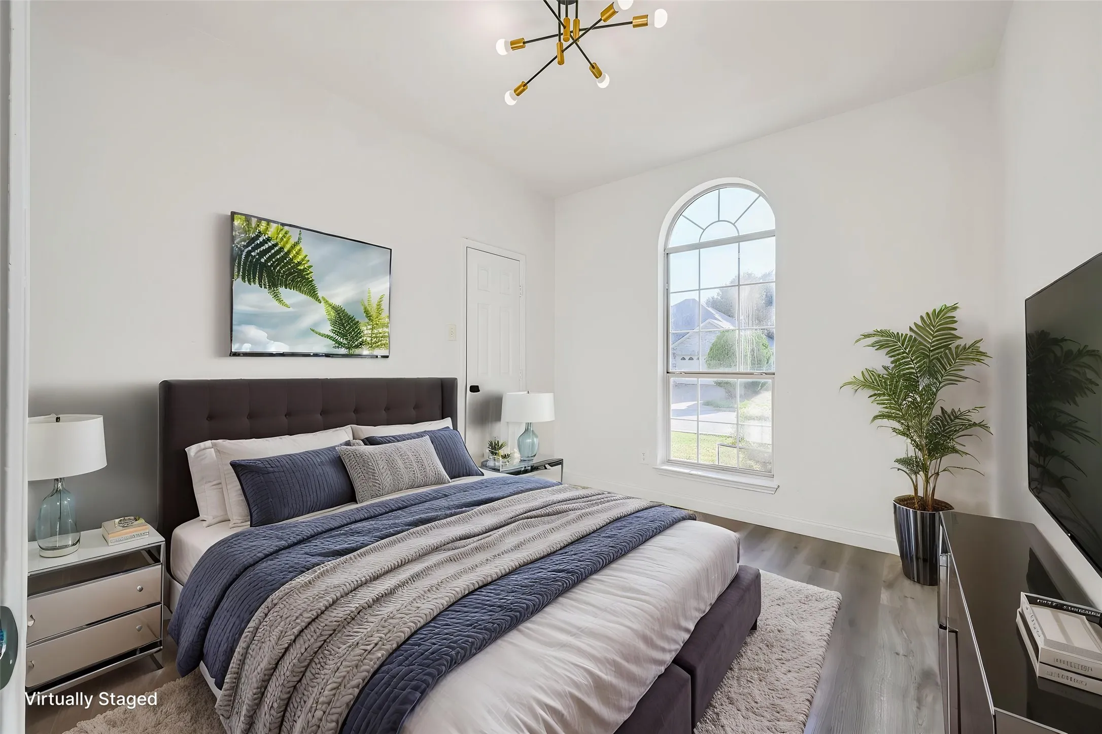 Room featuring a prominent arched window, wood-finish flooring, and a modern sputnik chandelier