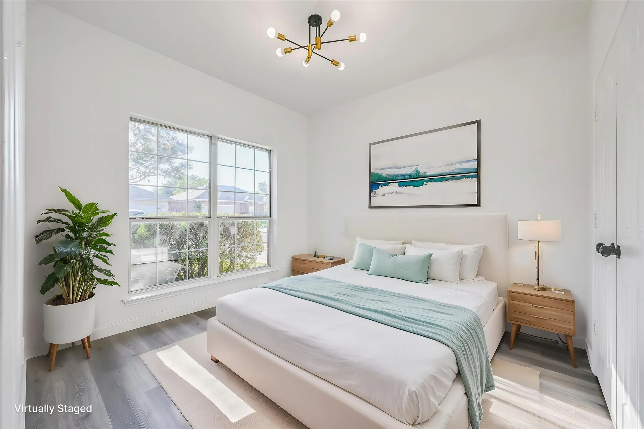 Spacious room featuring large windows with grid patterns, light-toned wood-finish flooring, and a modern ceiling fixture