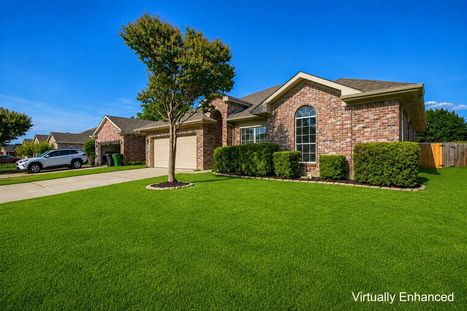 Brick facade home with an arched window, a two-car garage, and established landscaping
