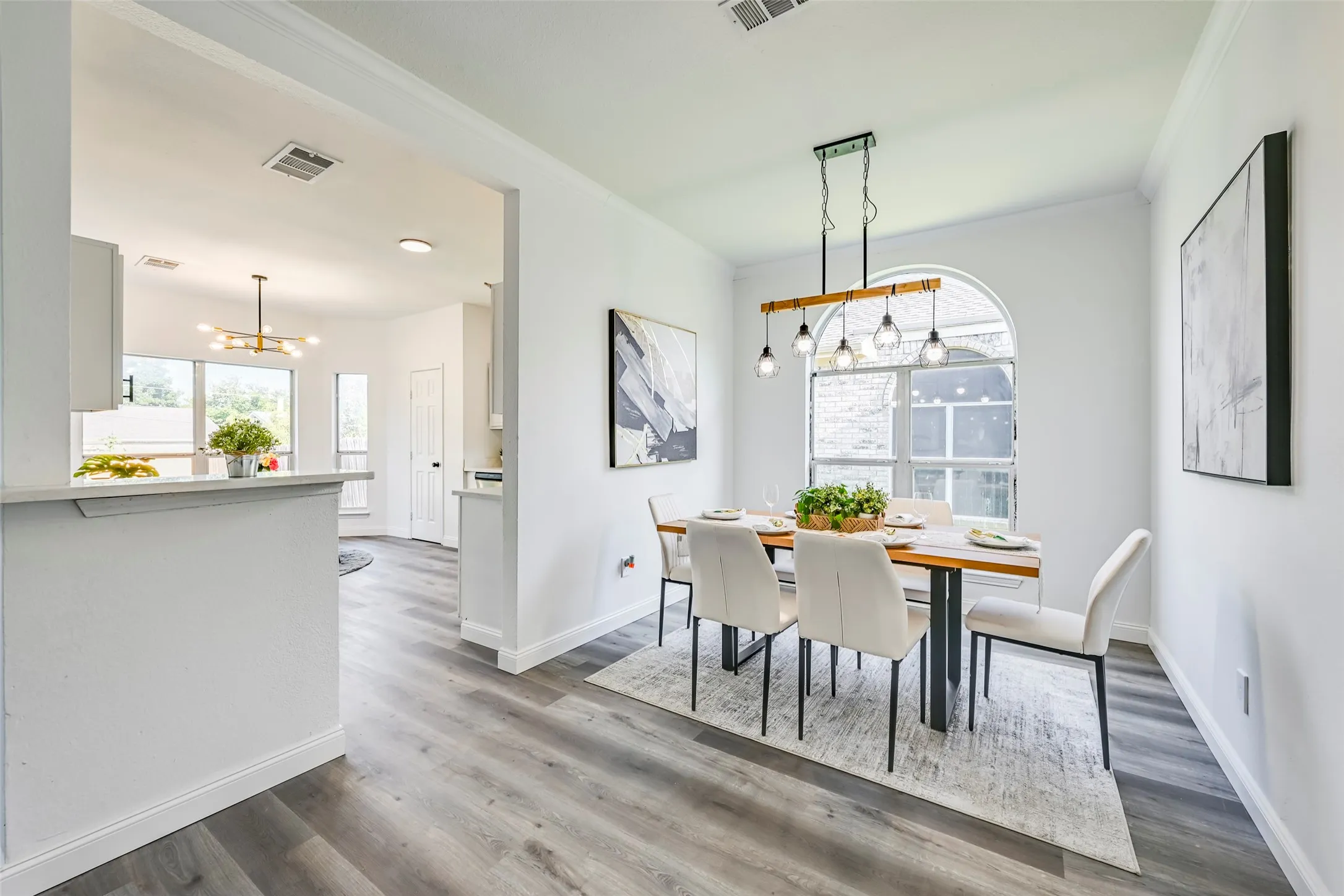 Dining area featuring wood-finish flooring, an arched window, and a linear pendant light fixture