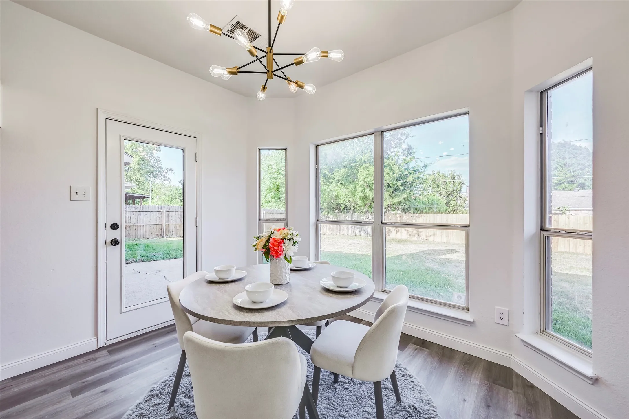 Dining area featuring wood-finish flooring, a modern sputnik-style light fixture, multiple large windows, and a glass-paneled exterior door