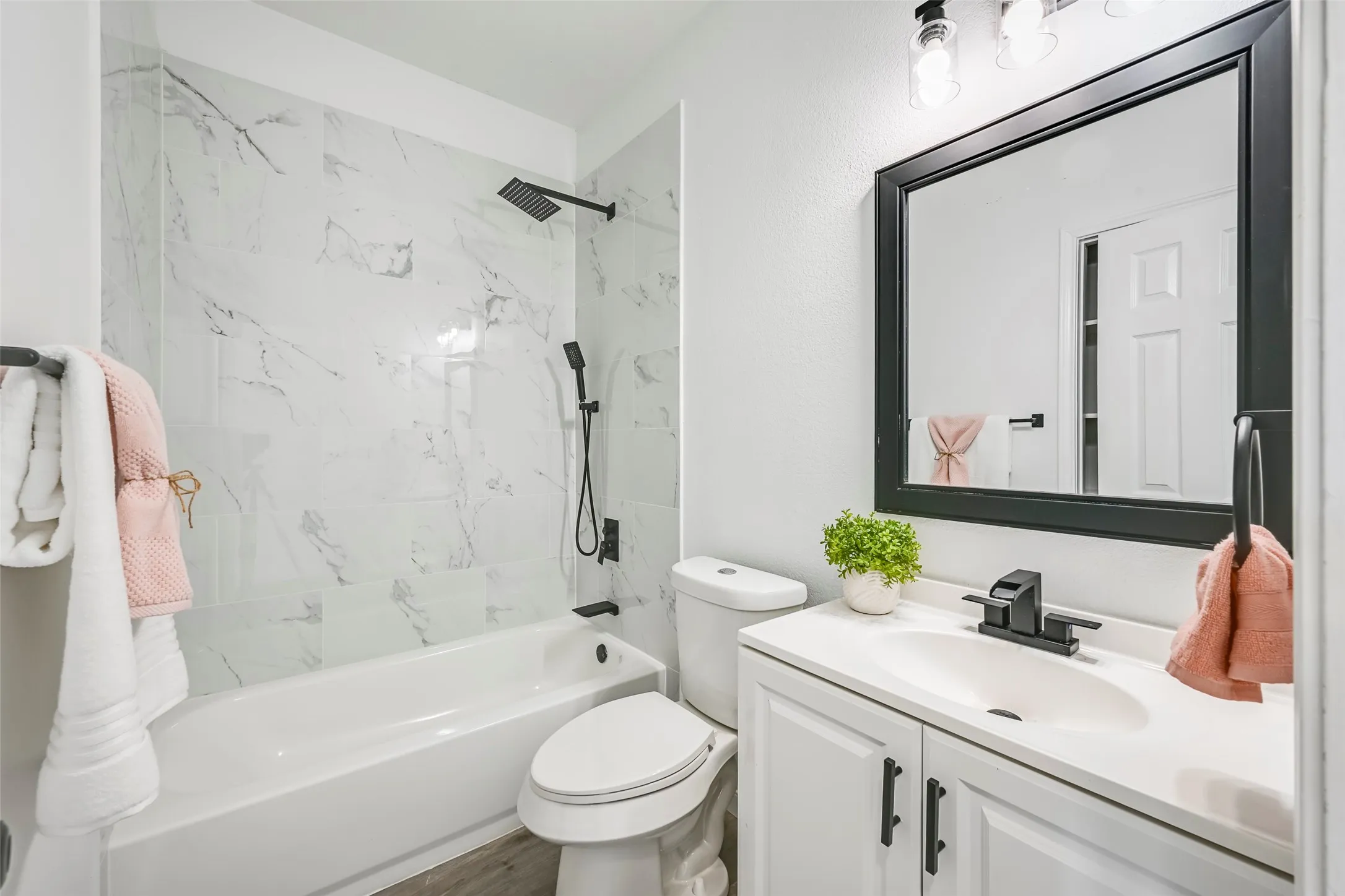 Bathroom with a white vanity featuring a single sink and matte black faucet, framed mirror, and a toilet