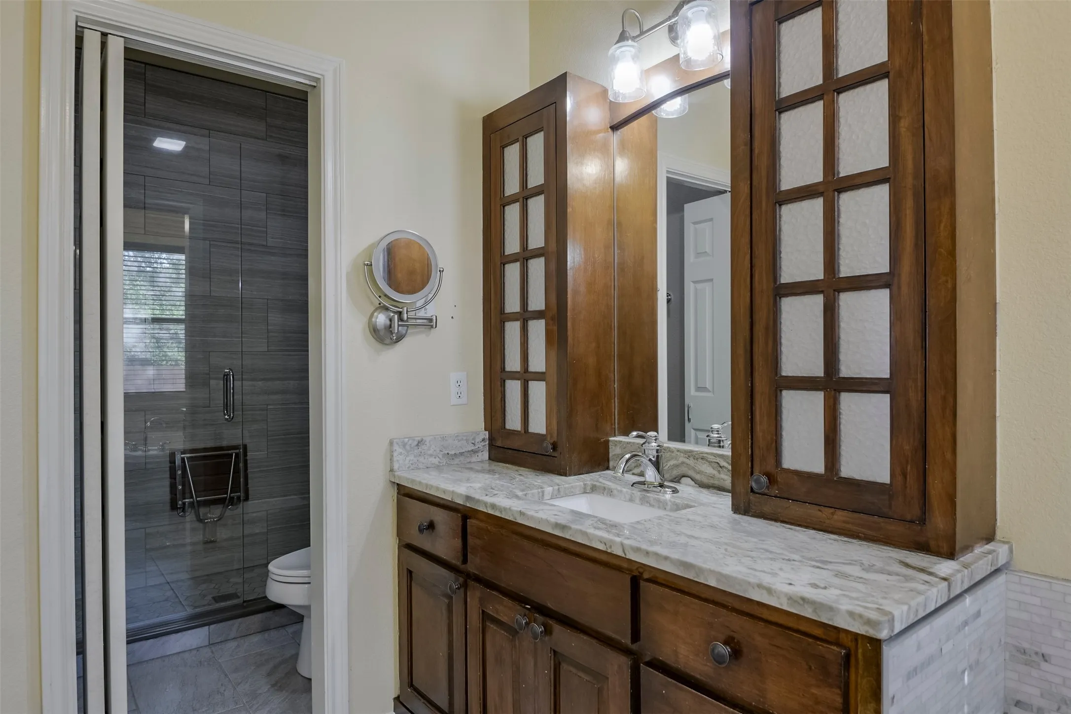Vanity with a light-toned stone countertop, integrated sink, and dark wood cabinetry