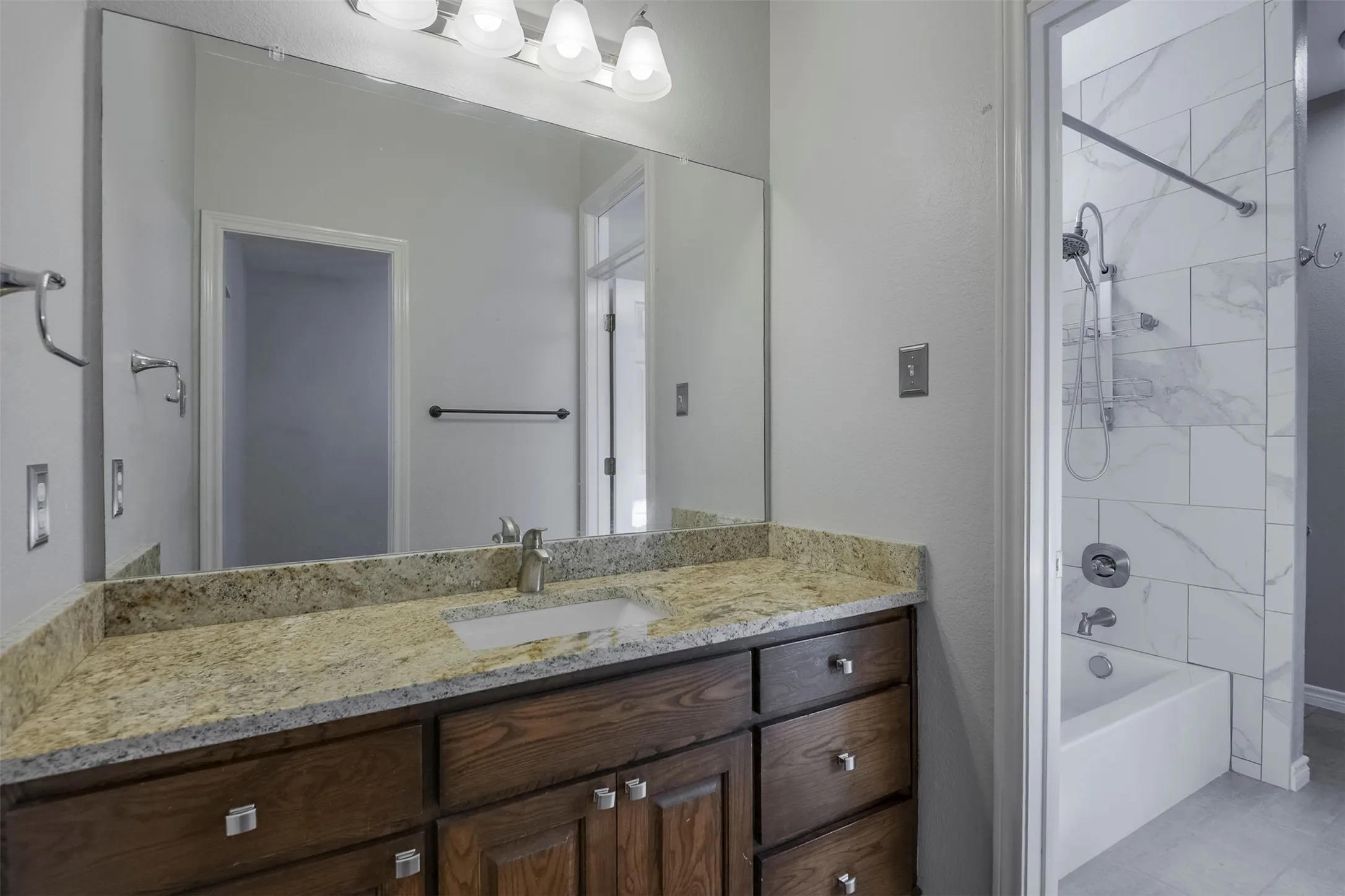 Bathroom featuring an expansive vanity with a granite countertop, undermount sink, and wood cabinetry