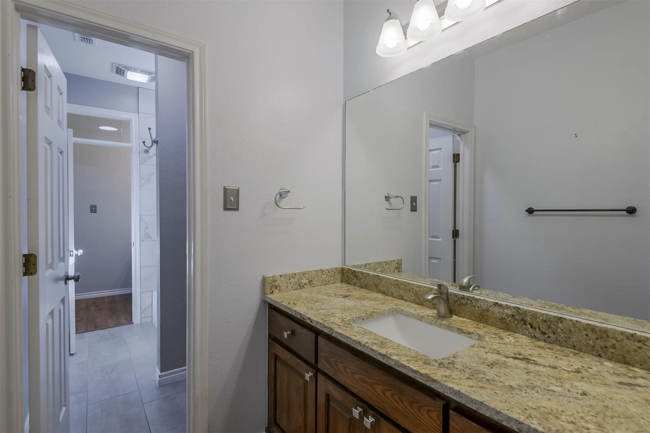 Bathroom vanity with granite countertop, integrated sink, and wood-finish cabinetry