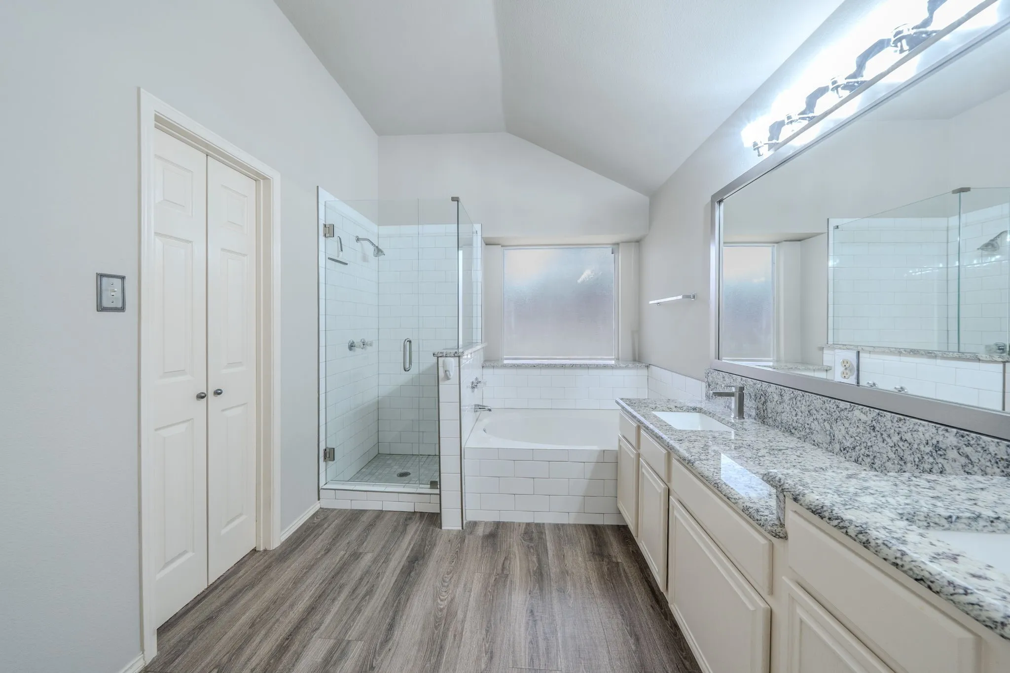 Enjoy a separate frameless shower and a garden tub beneath a bright picture window