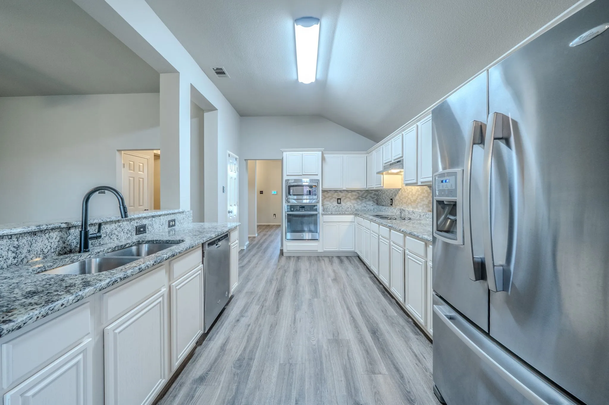 The spacious kitchen features granite counters, stainless steel appliances, and ample cabinet and counter space.