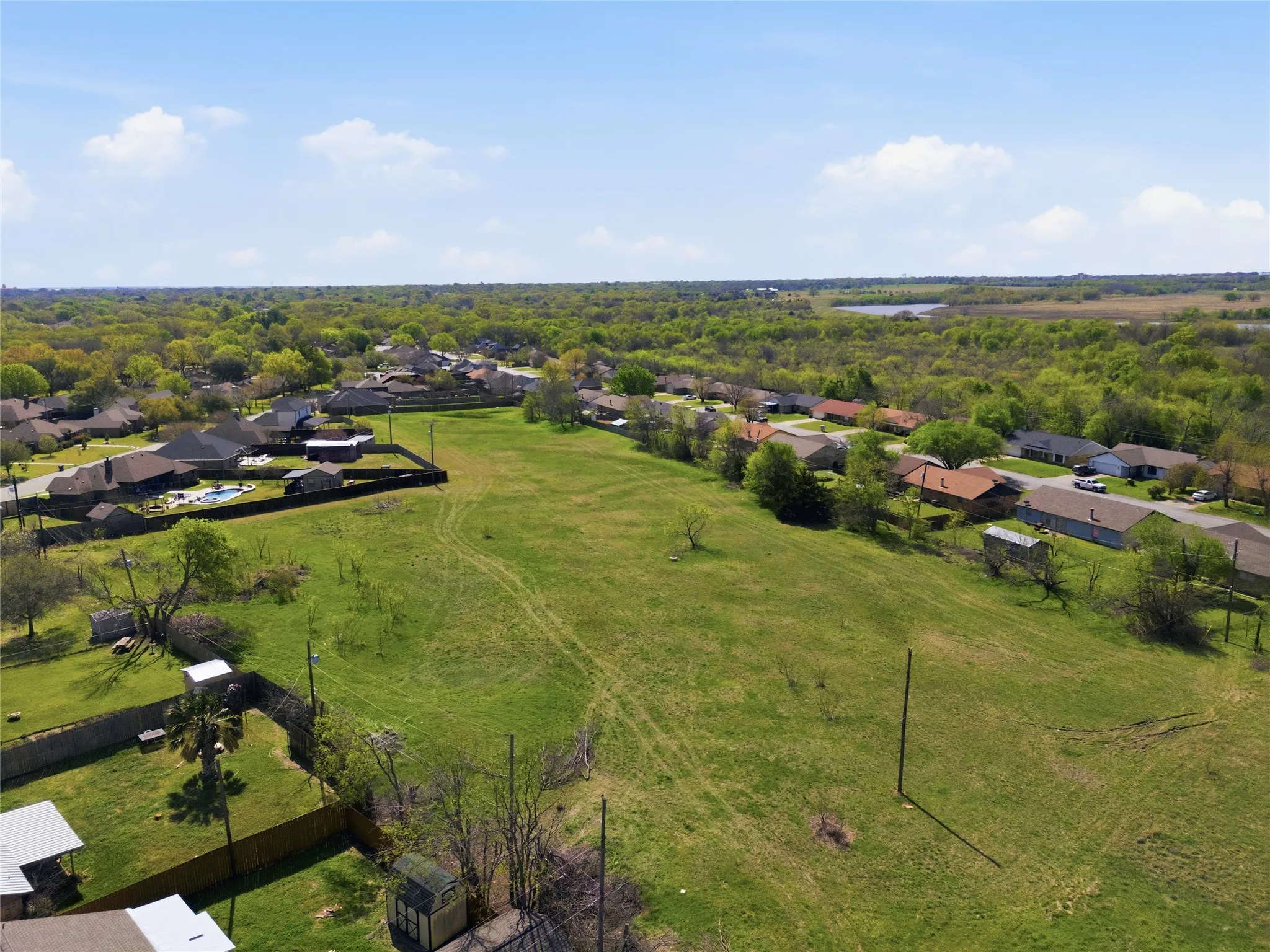 Expansive grassy lot bordered by established residences and mature trees
