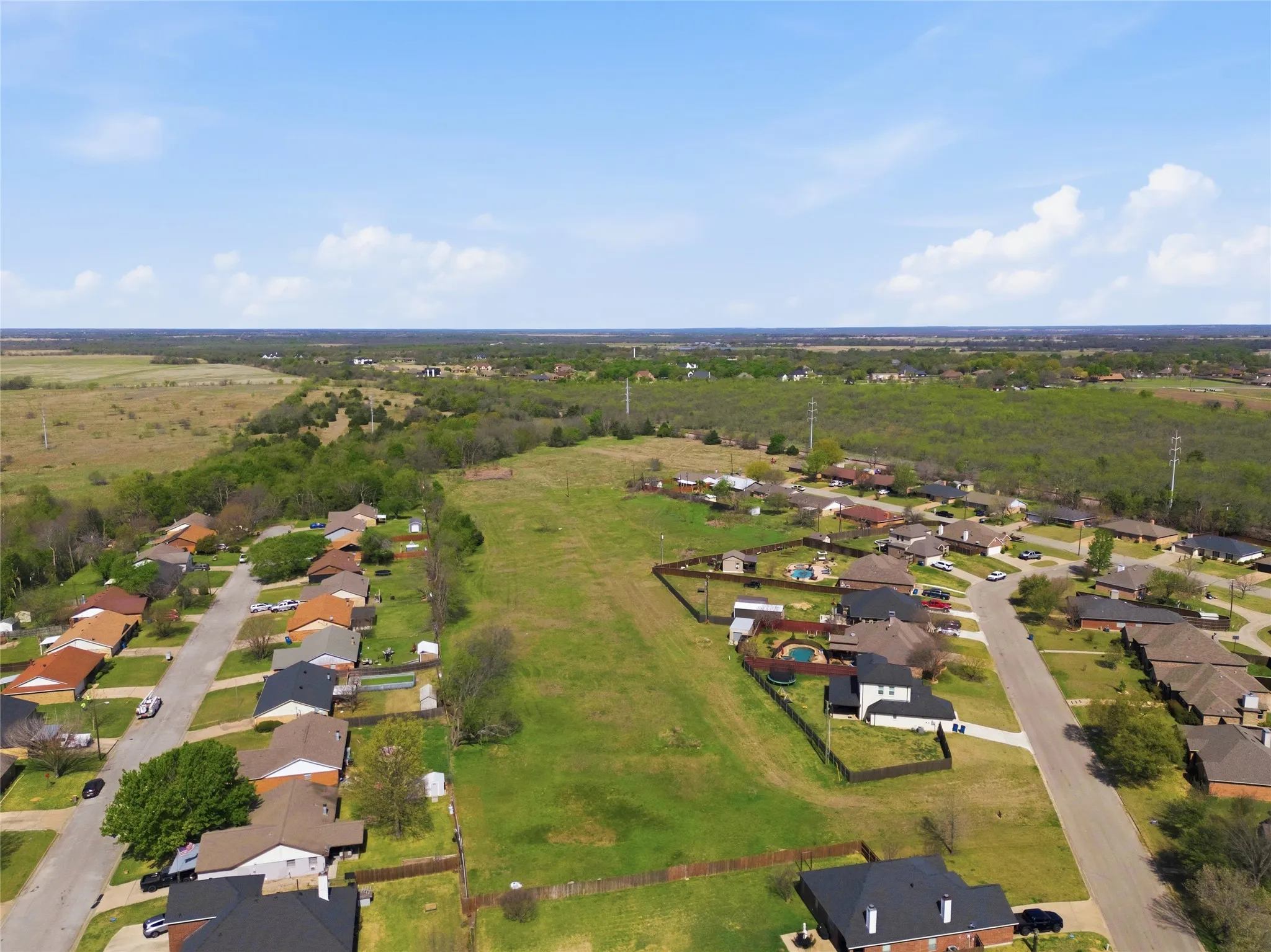 Expansive green space bordered by residential homes and distant treelines